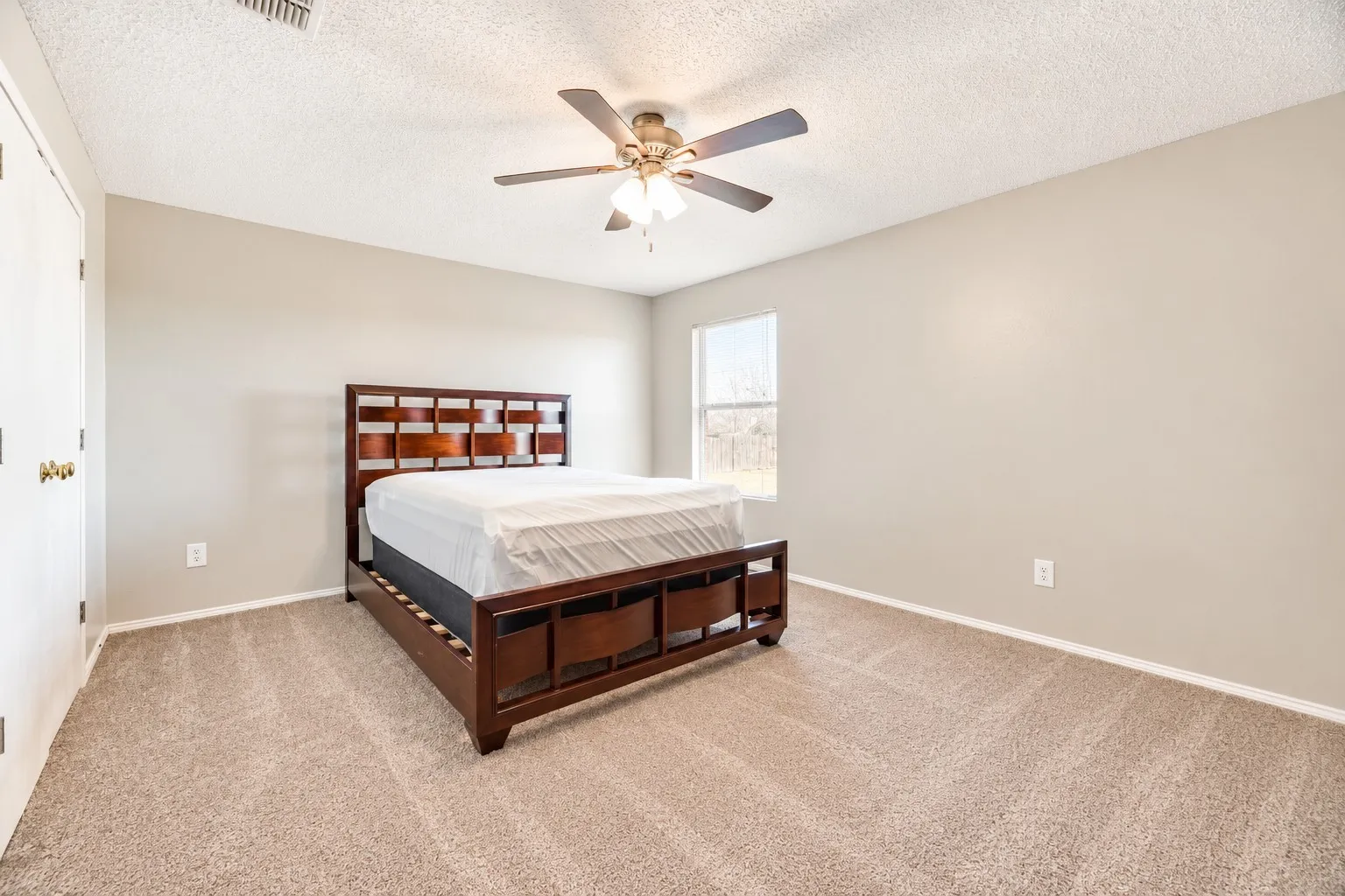 Neutral-toned walls, carpeted flooring, and a ceiling fan with integrated lighting