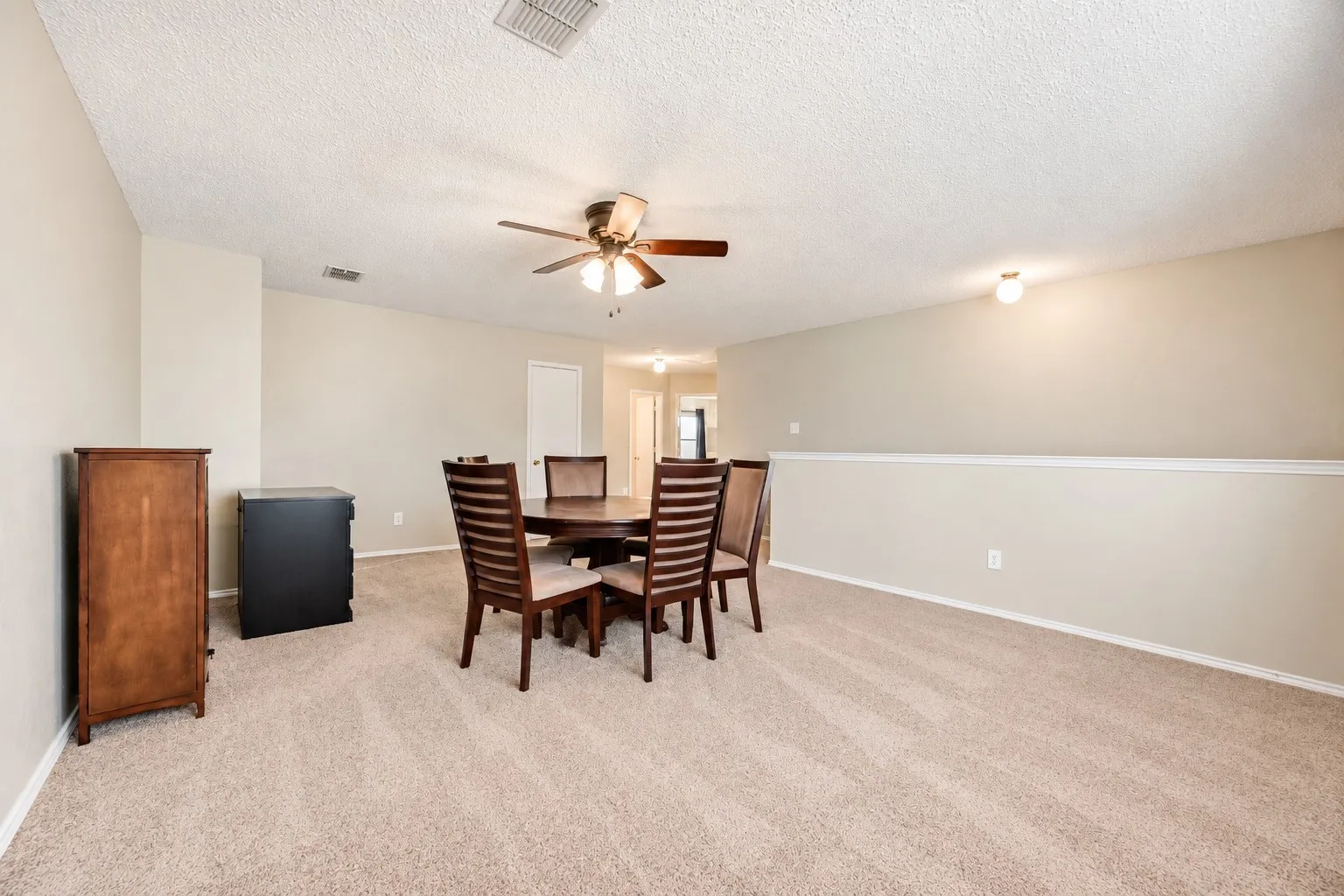 Carpeted common area featuring a ceiling fan, neutral wall paint, and a half-wall partition with a white cap