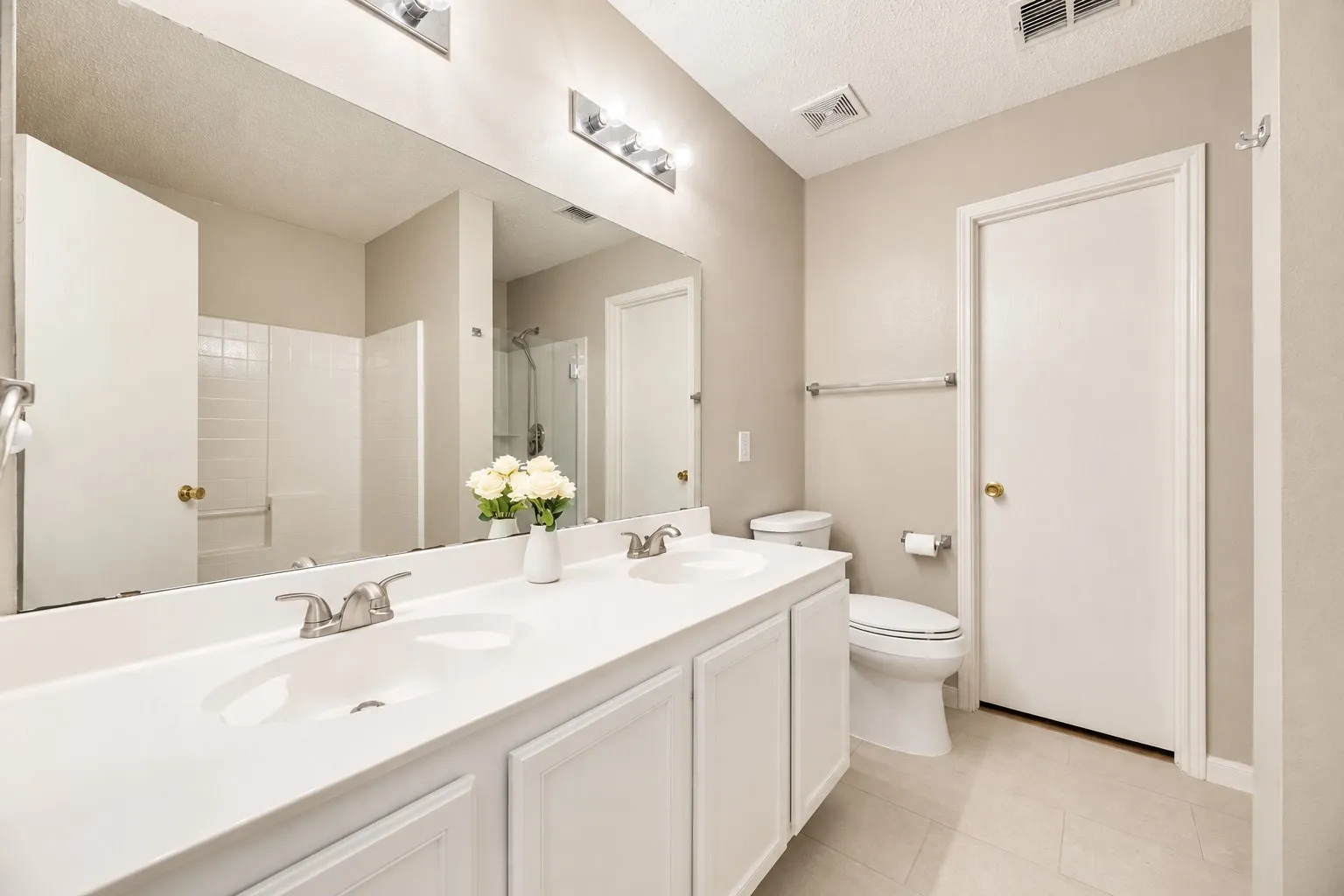 Dual undermount sinks with brushed nickel faucets, expansive vanity mirror, and recessed overhead lighting