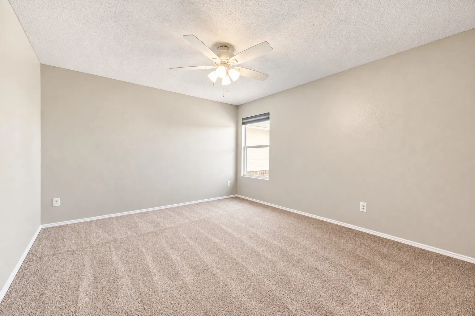 Neutral wall color palette, window with blinds, textured ceiling, ceiling fan with light fixture, and carpet flooring