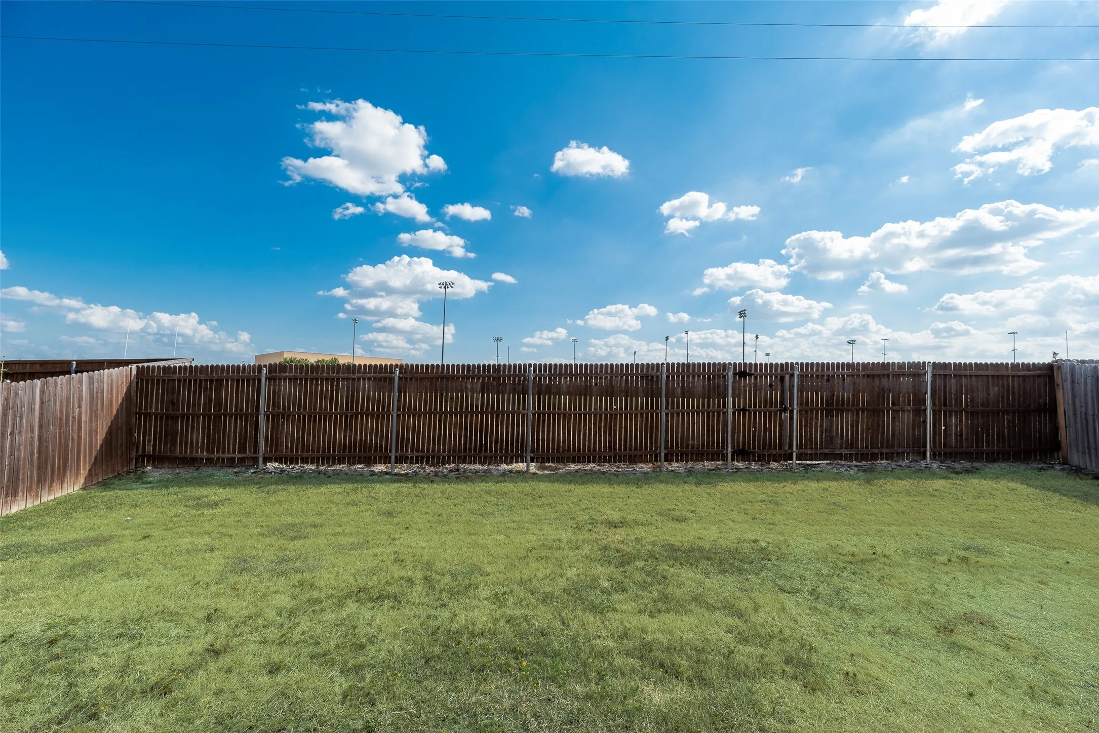 Expansive outdoor space featuring a large grassy area and perimeter fencing