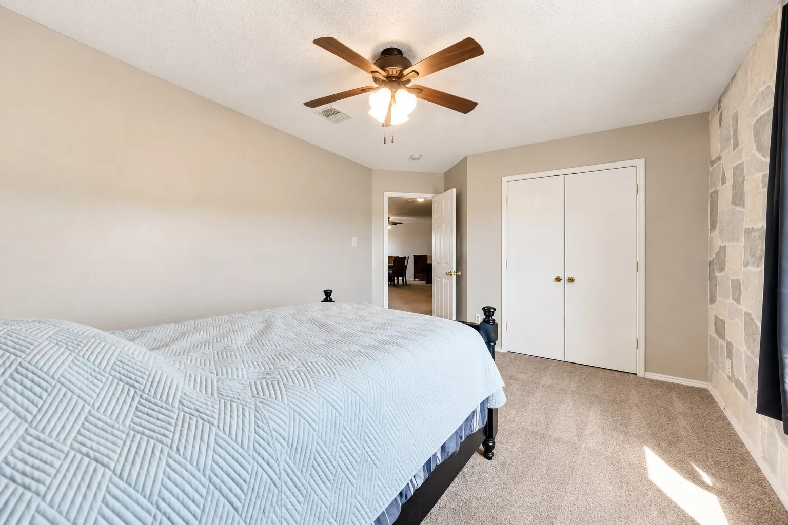Recessed ceiling fan, neutral wall paint, textured accent wall, carpet flooring, and bi-fold closet doors