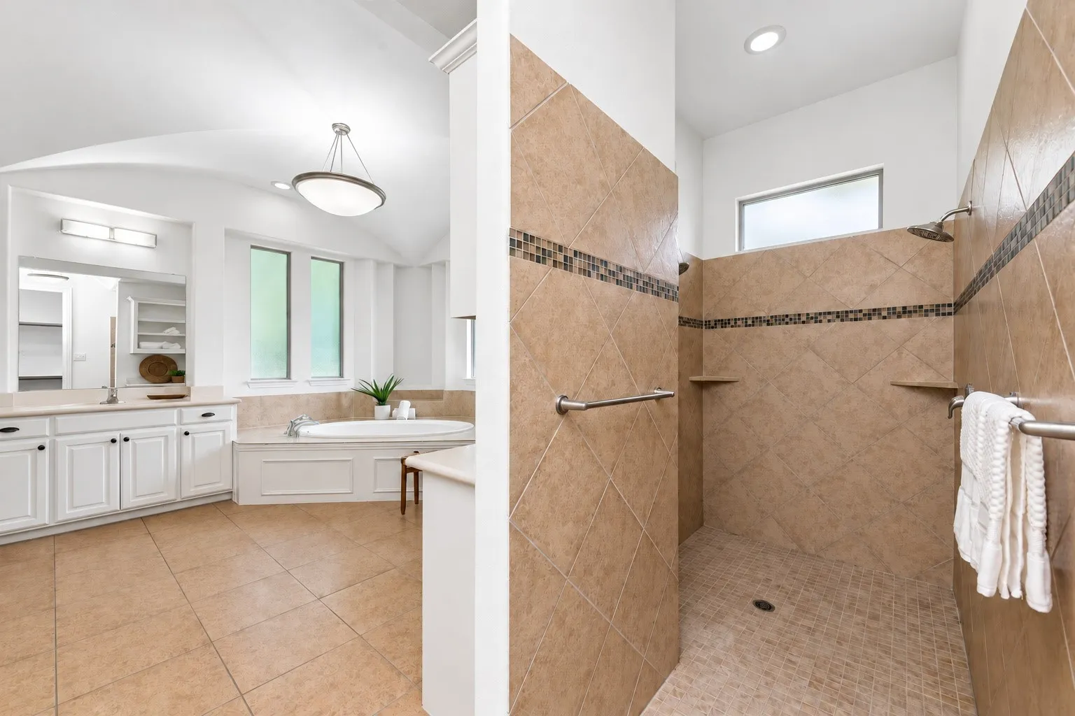 Spacious bathroom featuring a built-in soaking tub, dual vanity with undermount sinks, and a walk-in shower with tile surround and built-in shelving