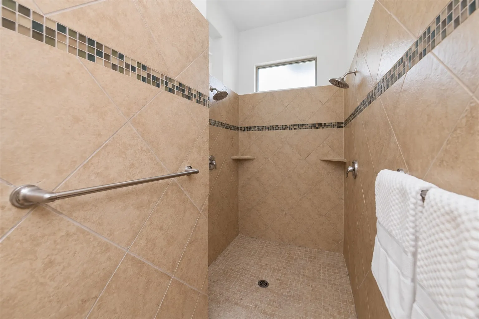 Tiled walk-in shower featuring dual shower heads, integrated shelving, and accent tile detailing