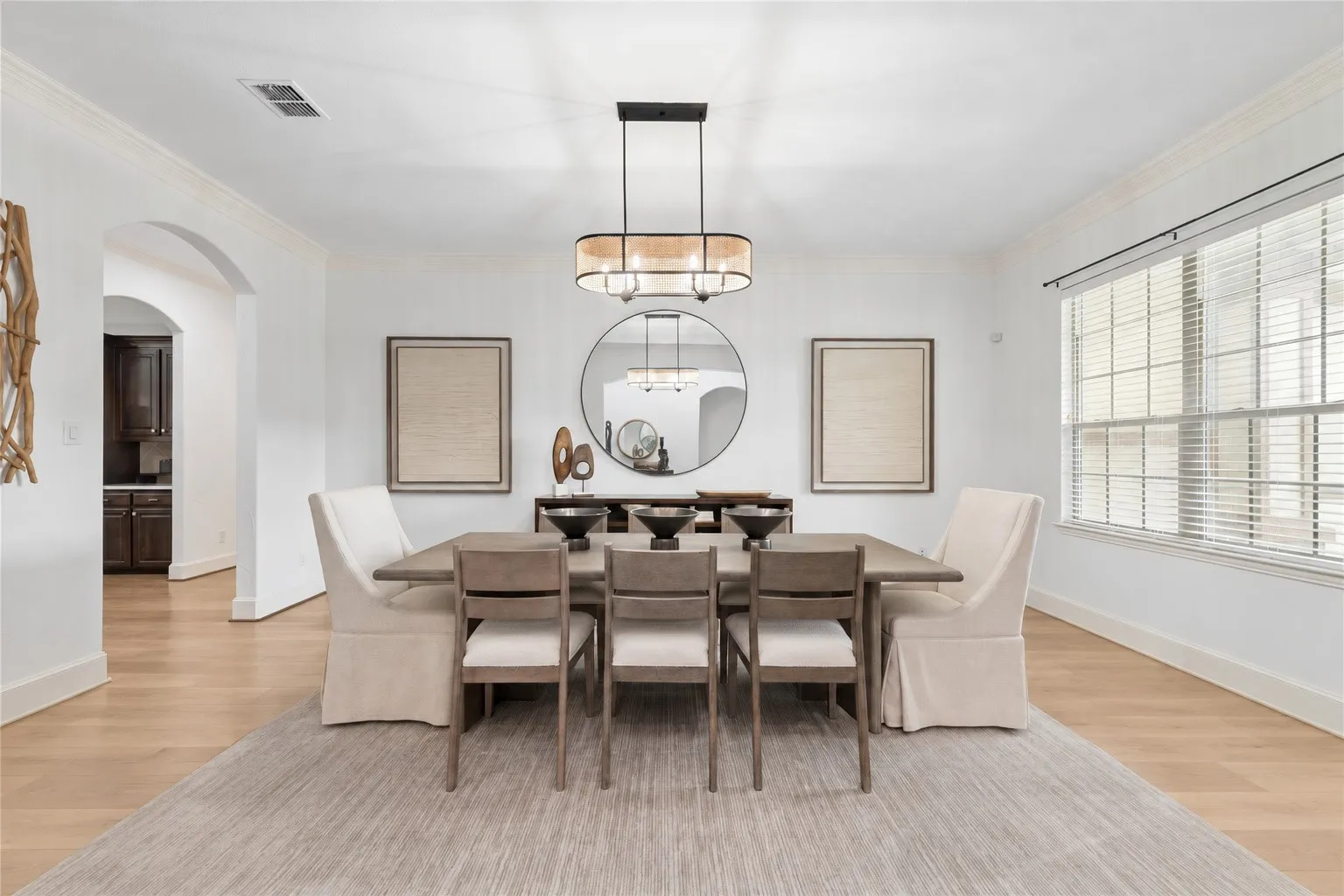 Expansive dining area featuring crown molding, wood-finish flooring, and a contemporary chandelier