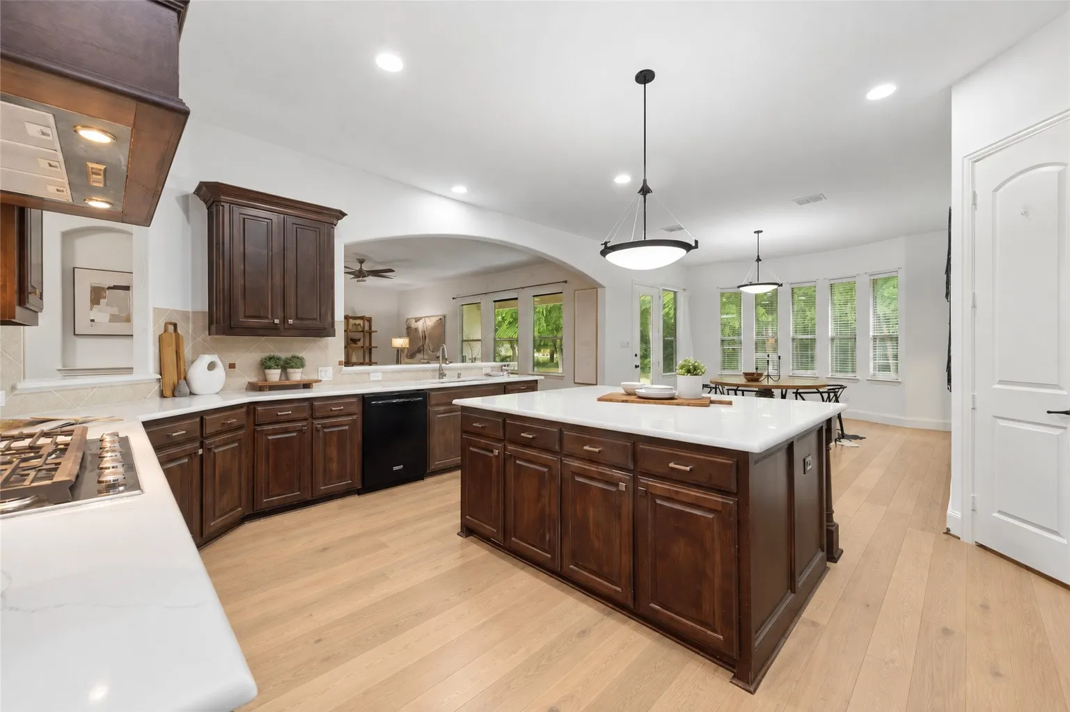 Kitchen featuring wood-finish flooring, dark wood cabinetry, light countertops, and a central island