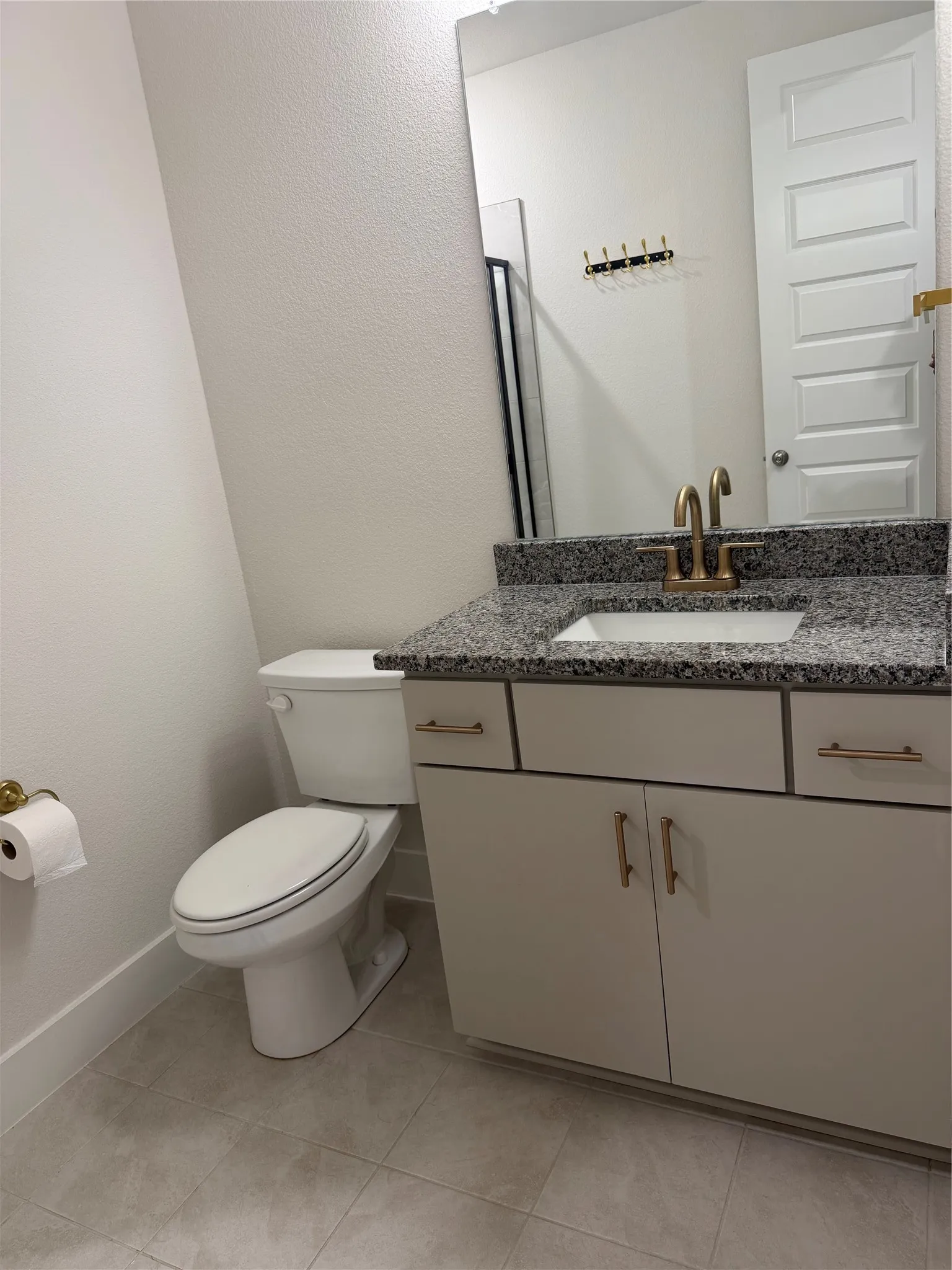 Modern vanity with a granite countertop, undermount sink, and brushed brass faucet