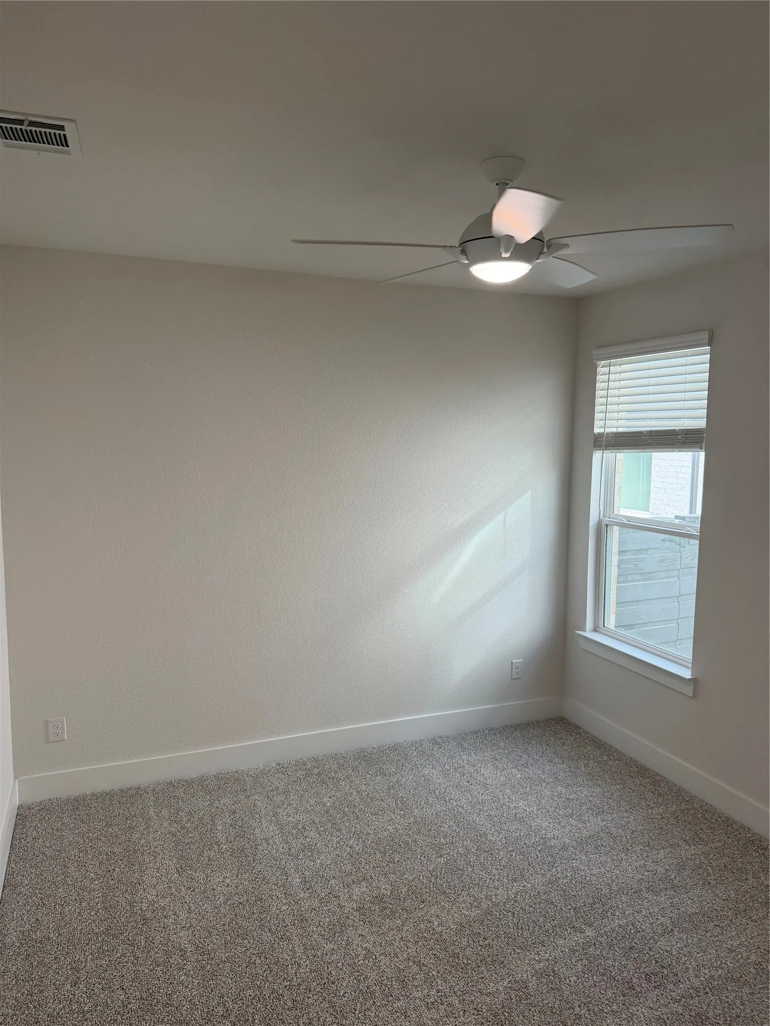 Plush carpet flooring, neutral paint palette, contemporary ceiling fan with integrated lighting, and a window with blinds