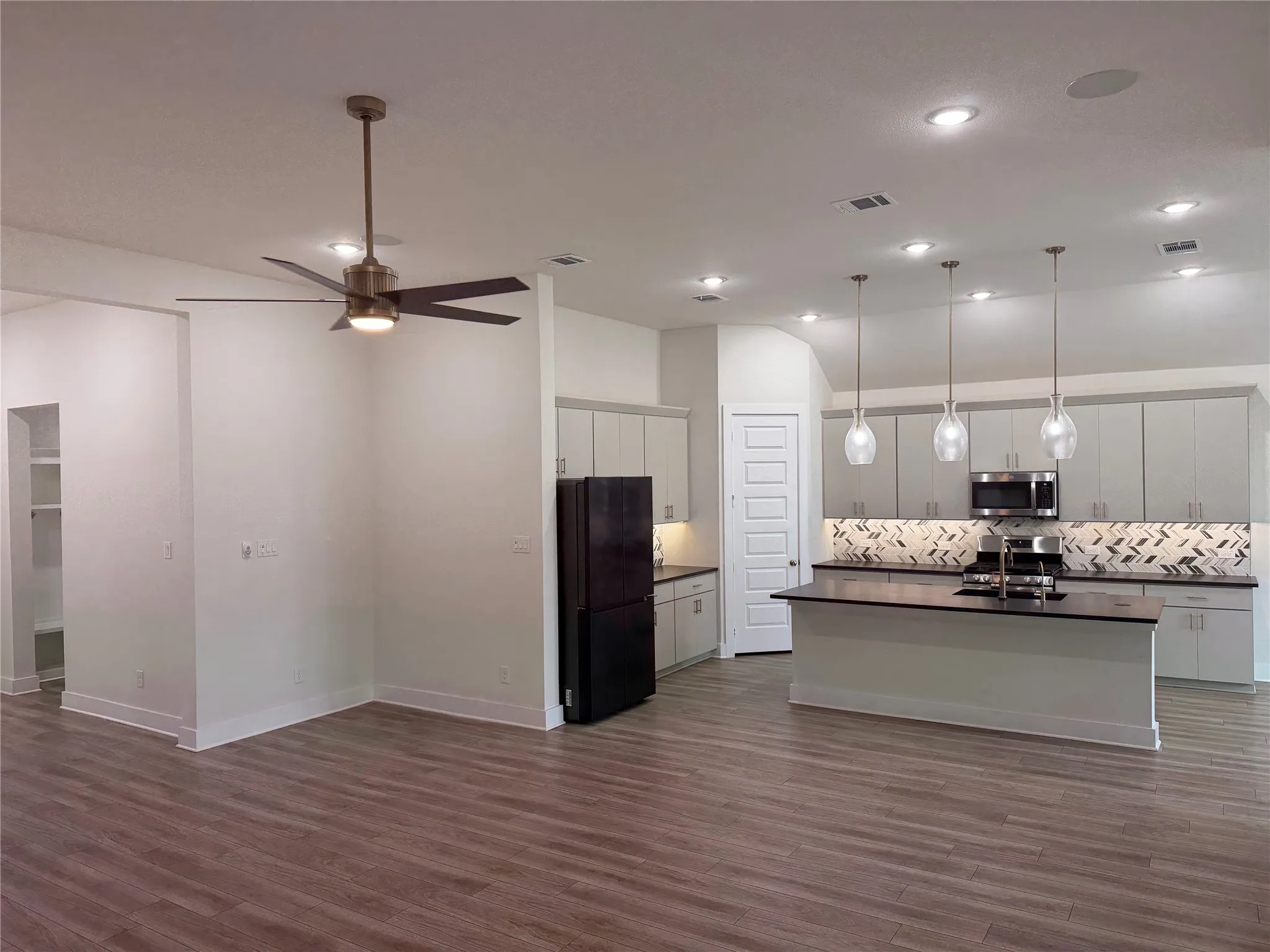 Open-concept living space featuring wood-finish flooring, a contemporary ceiling fan, and recessed lighting