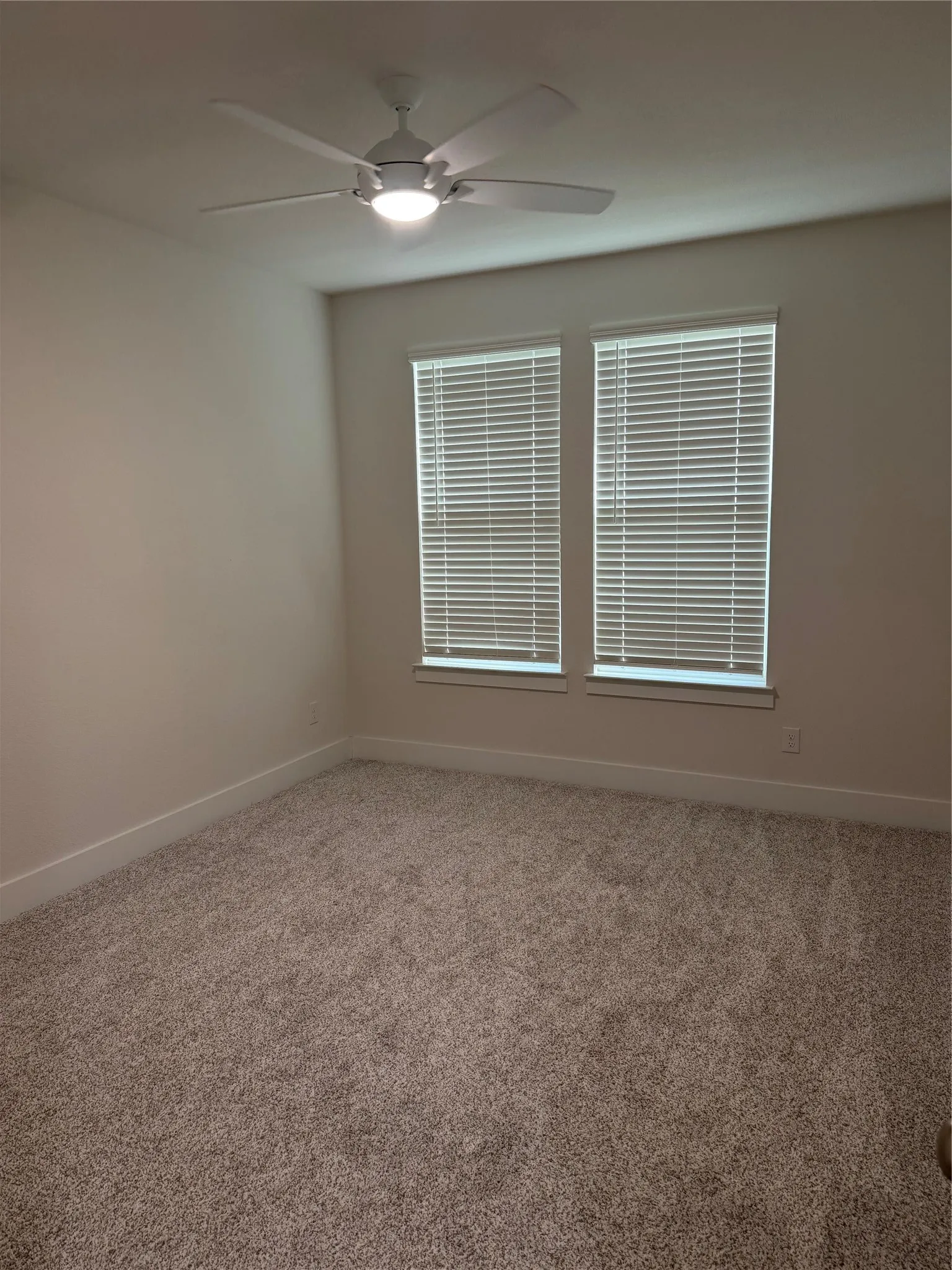 Two windows with blinds, ceiling fan with integrated lighting, and wall-to-wall carpeting