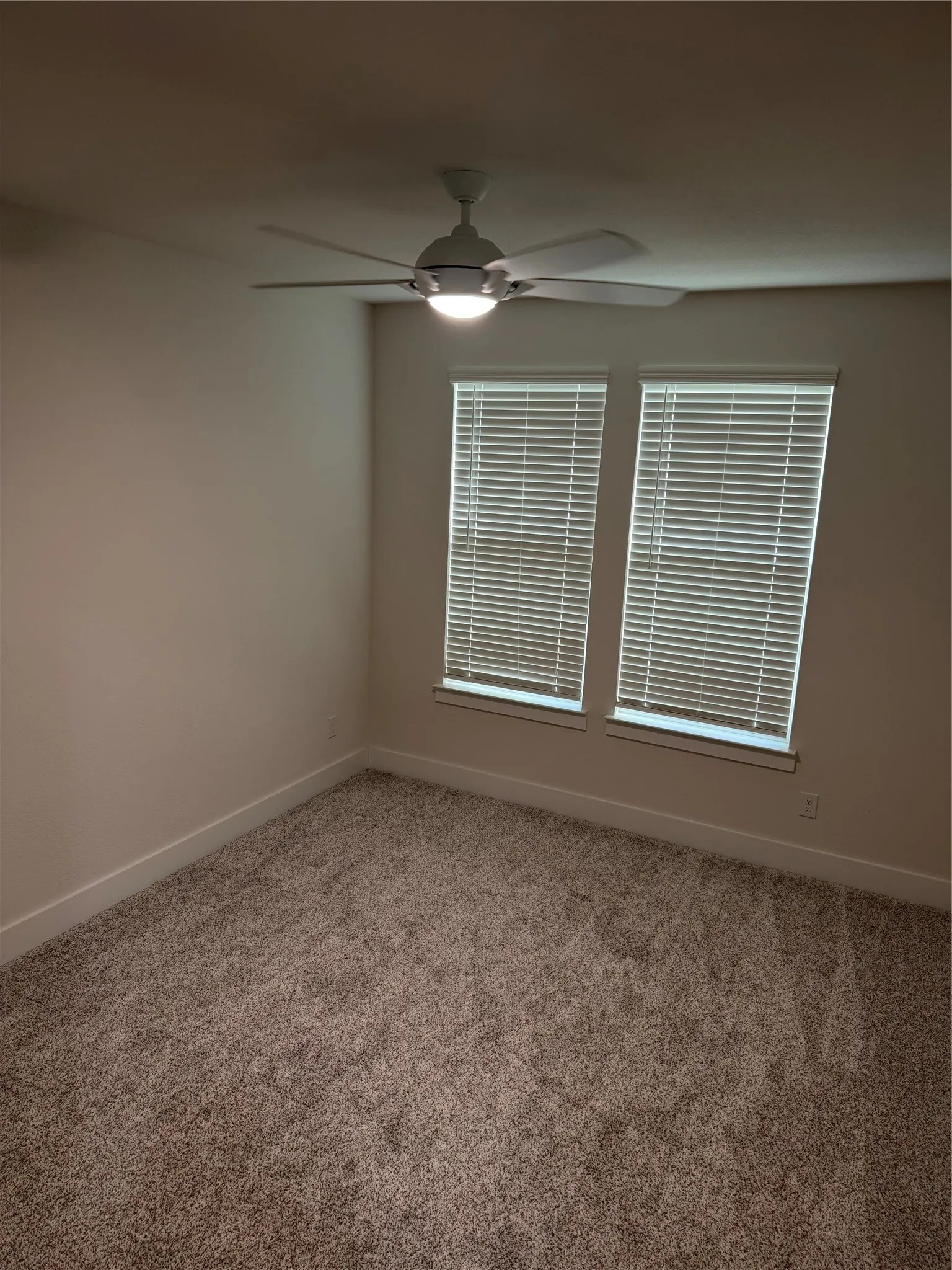 Two windows with blinds, ceiling fan with integrated lighting, and wall-to-wall carpeting