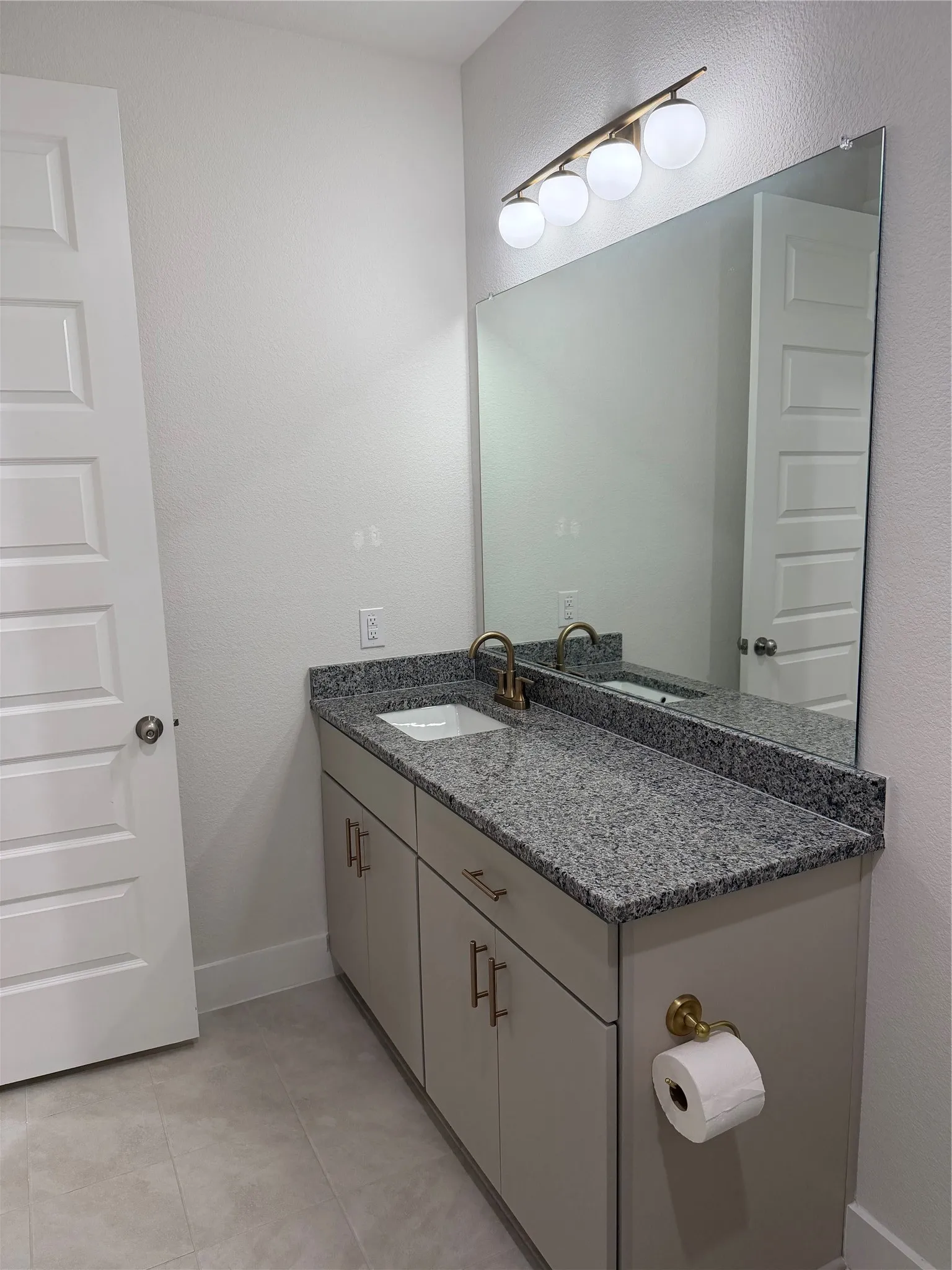 Vanity with speckled countertop, undermount sink, and brass-tone hardware