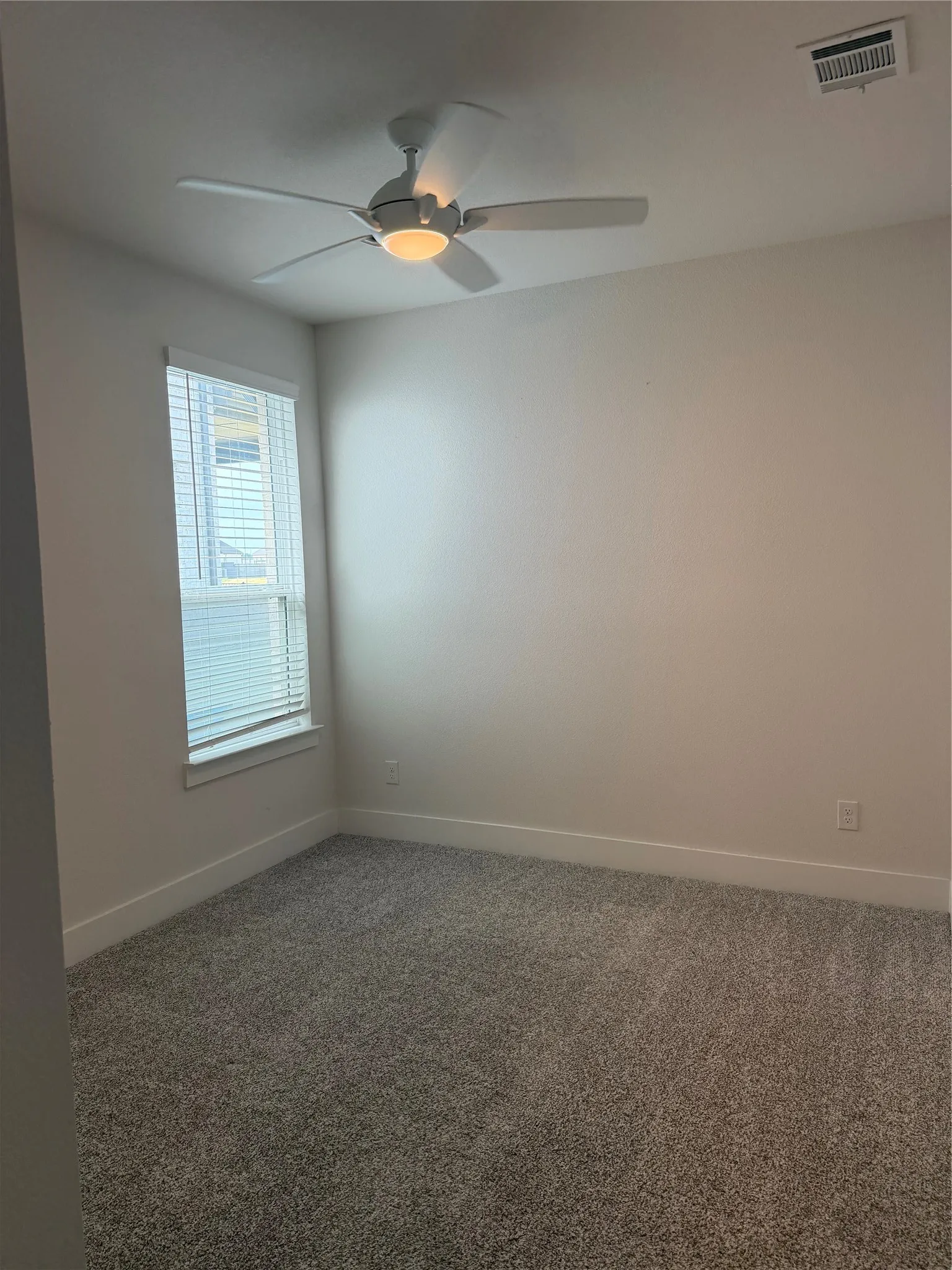 Window with blinds, ceiling fan with integrated lighting, wall-to-wall carpeting