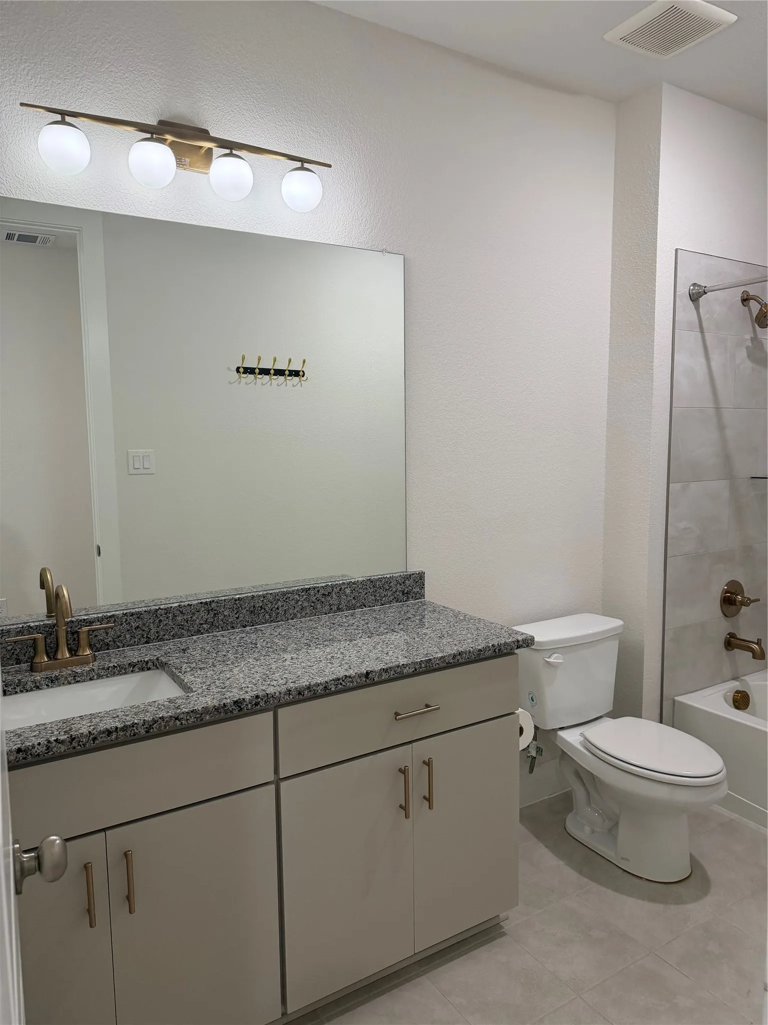 Vanity with a granite countertop, undermount sink, and bronze-finish faucet
