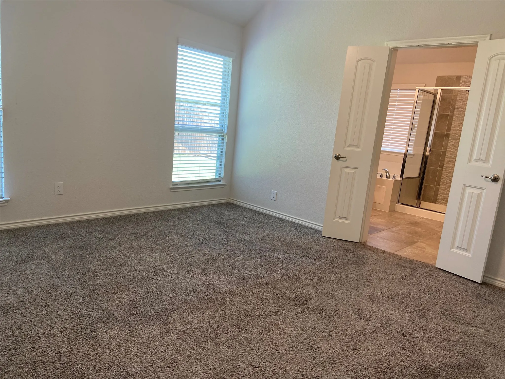 Unfurnished bedroom with carpet flooring and ensuite bathroom