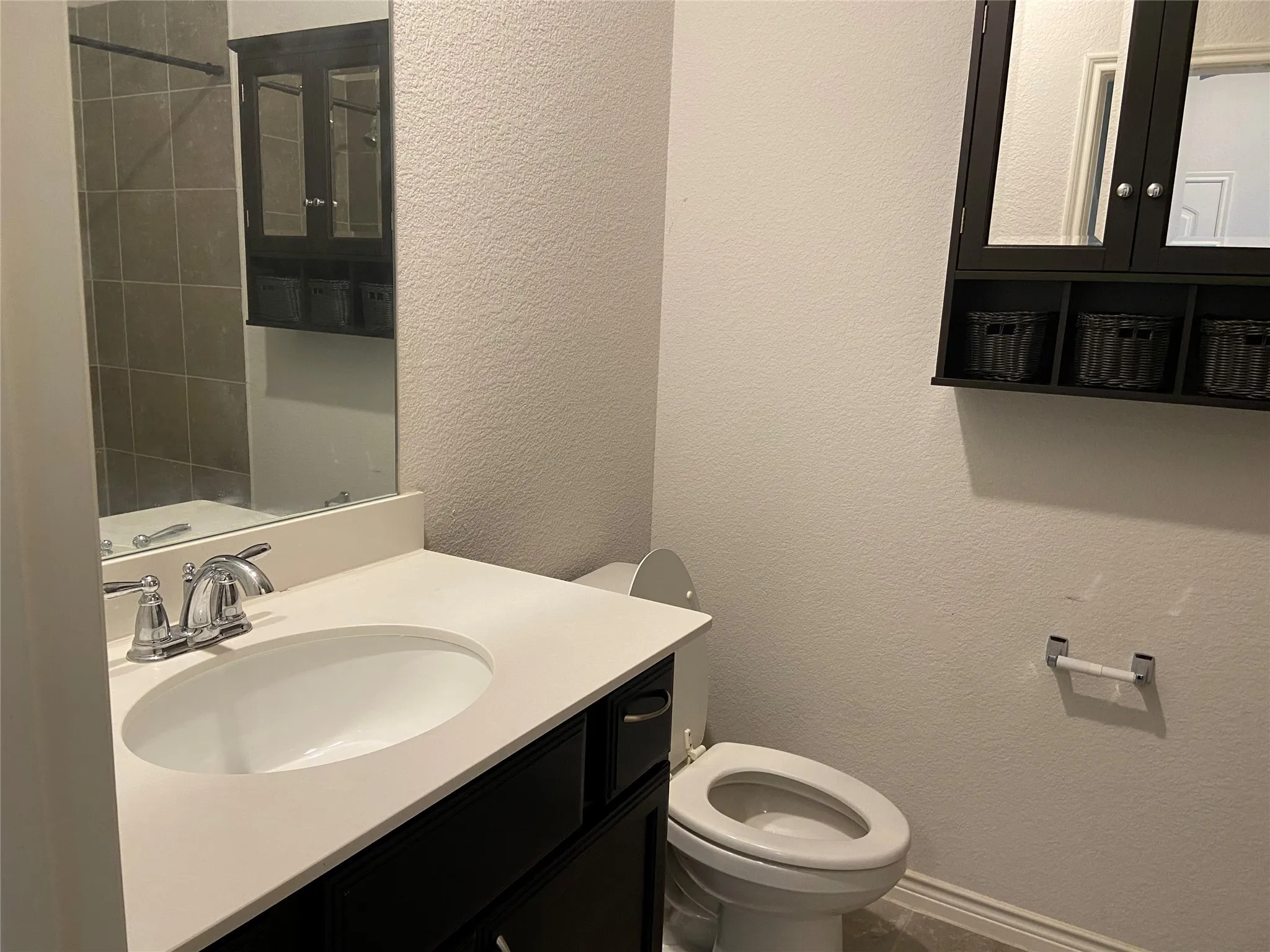Full bathroom featuring a textured wall, vanity, and a shower