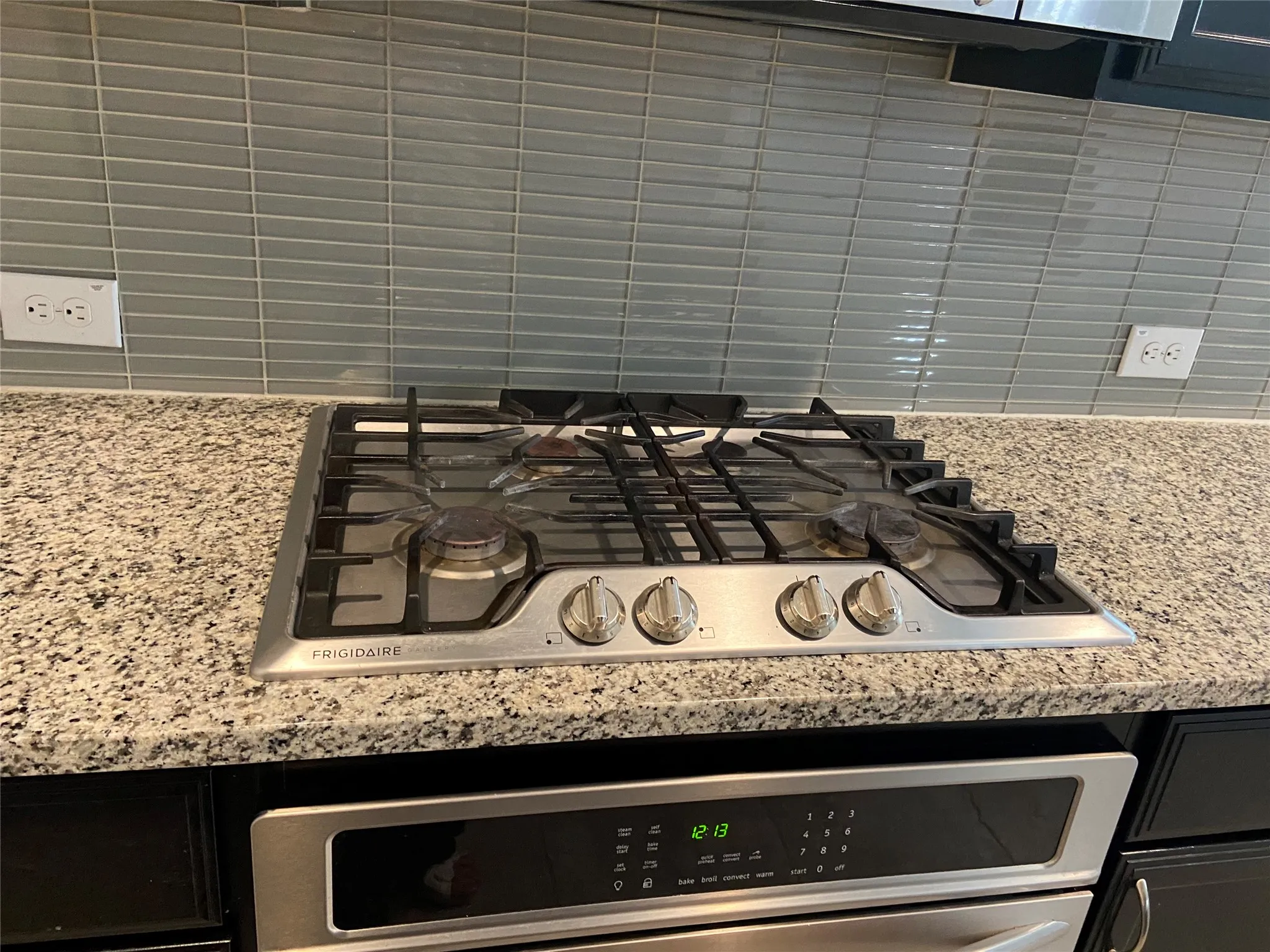 Kitchen view of light stone countertops, stainless steel appliances, and dark cabinetry