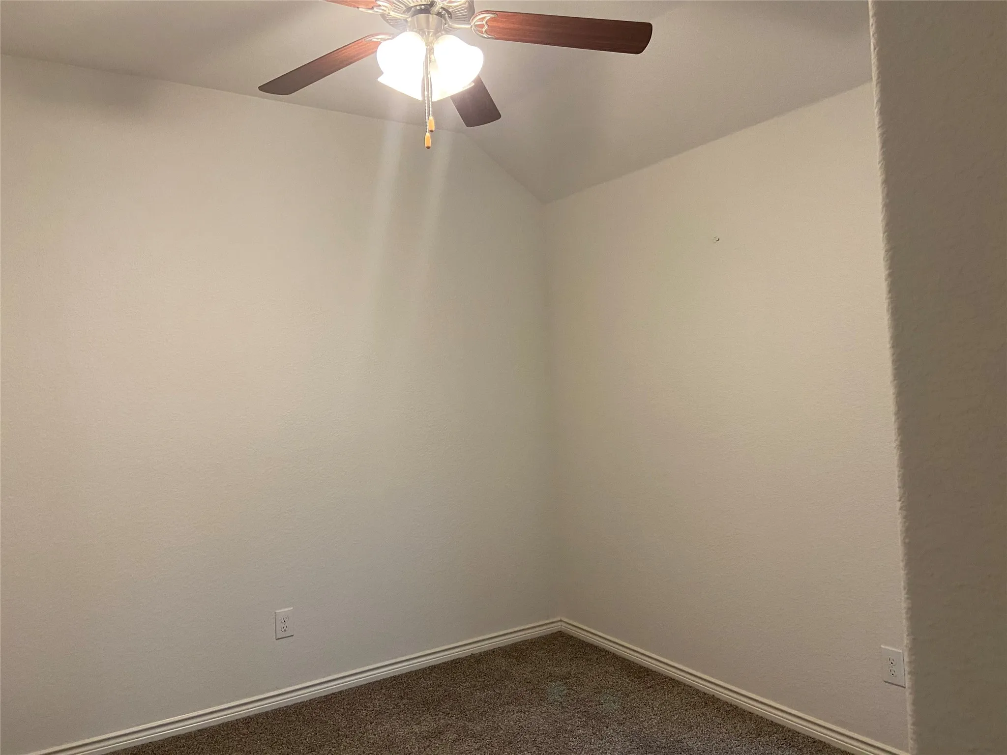 Spare room with dark colored carpet and a ceiling fan