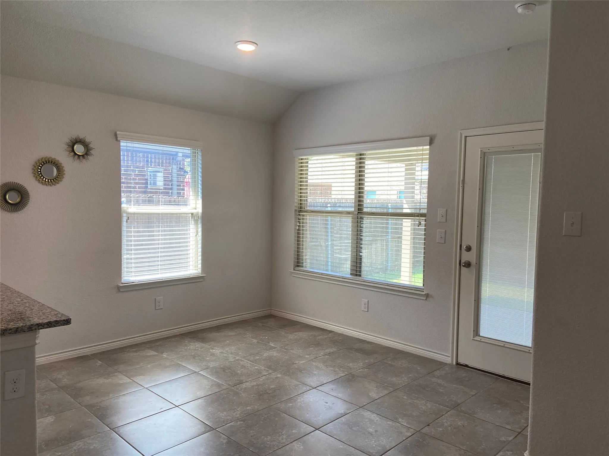 Unfurnished dining area with vaulted ceiling and light tile patterned floors
