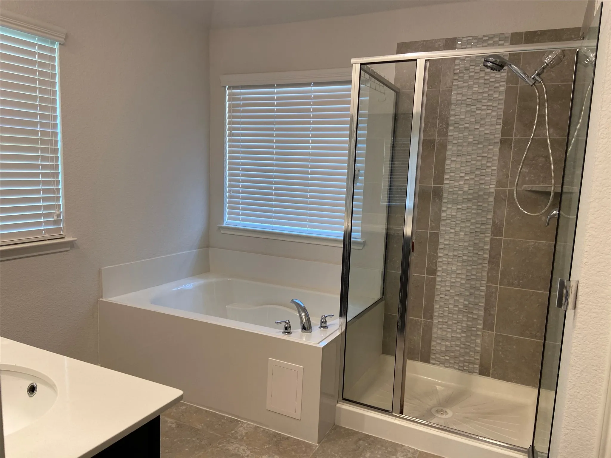 Bathroom featuring vanity, a garden tub, a stall shower, and a textured wall