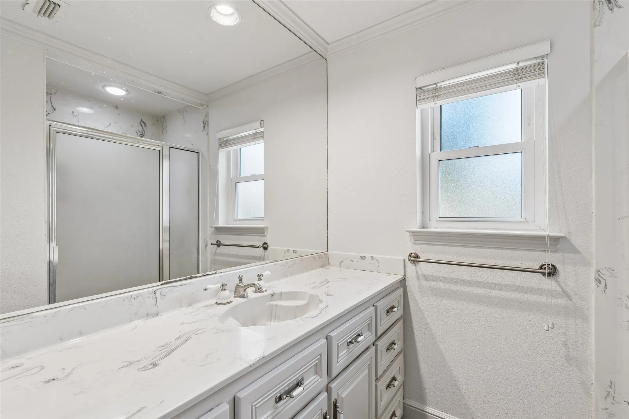 Vanity with an integrated sink, polished chrome faucet, and stone-finish countertop