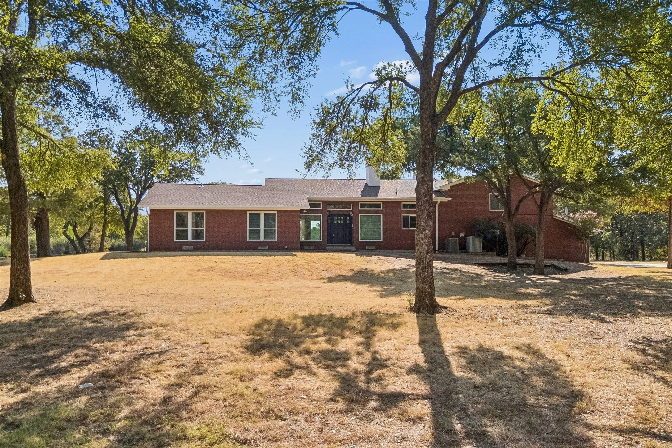 Red brick exterior with white trim windows and a dark entry door