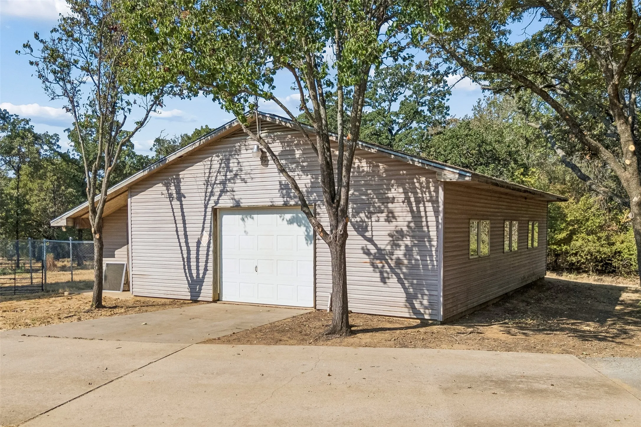 Detached structure with horizontal siding, a white garage door, and multiple windows