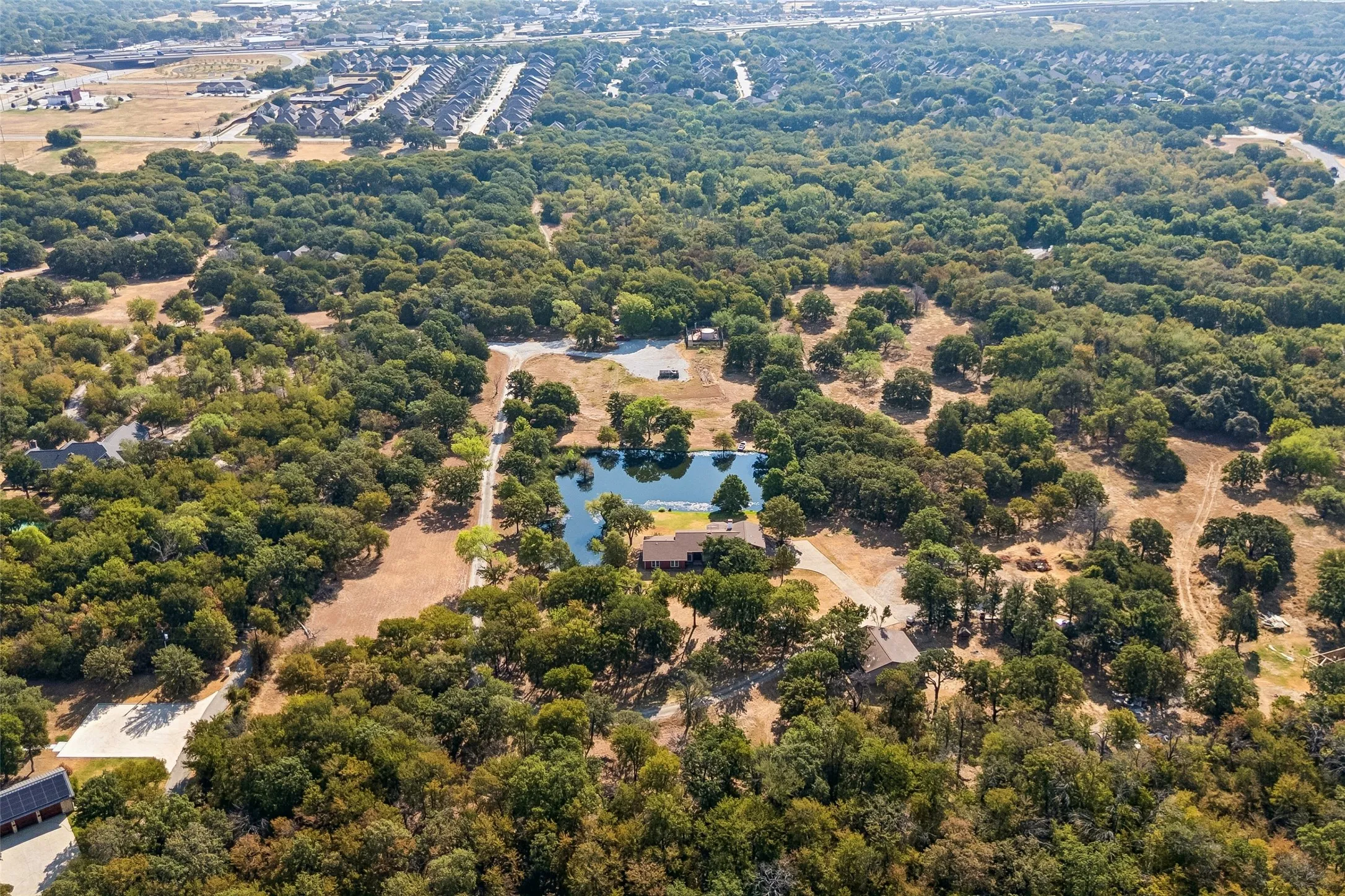Expansive grounds with mature trees, a private pond, and a winding paved driveway