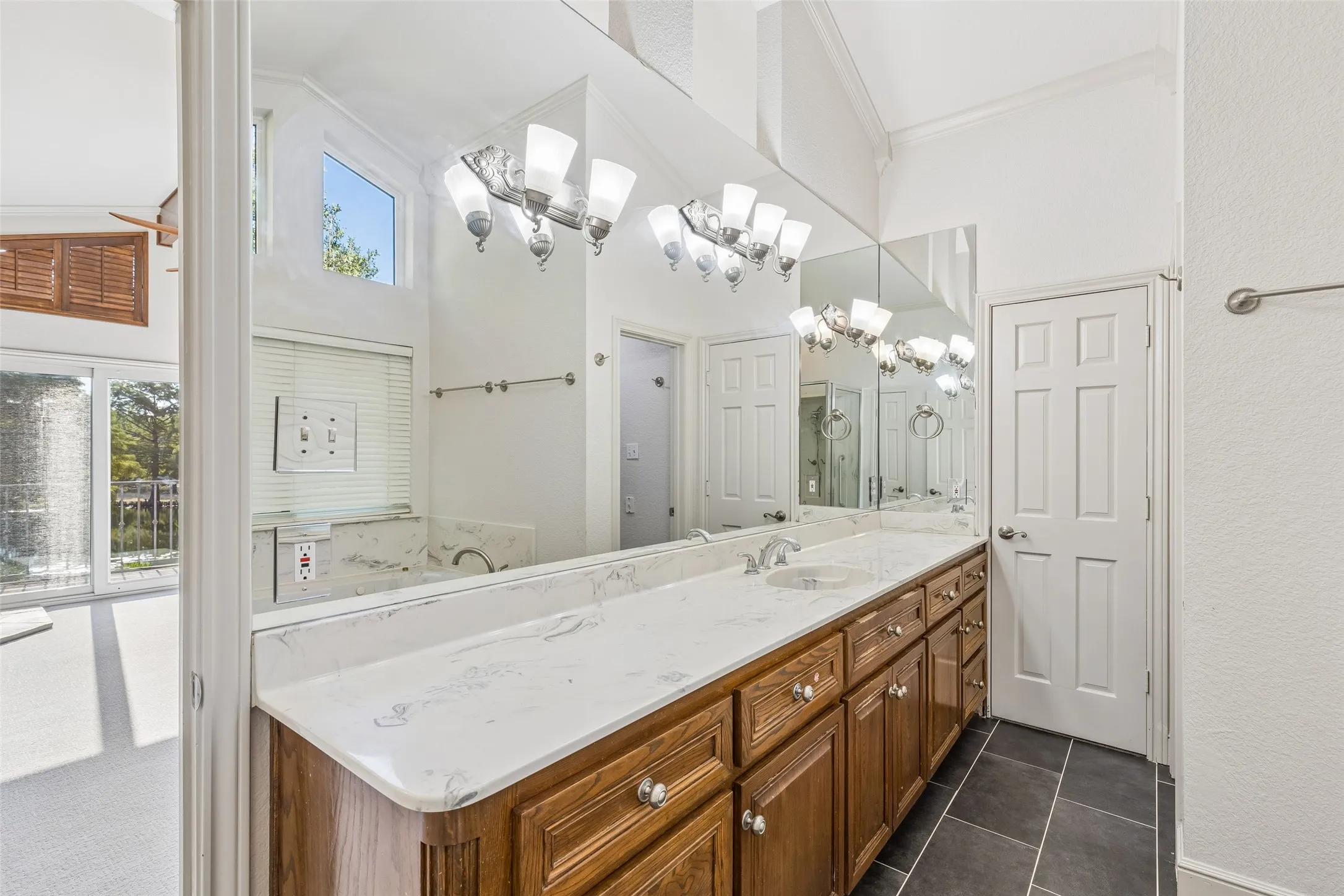 Dual vanity with white countertop, integrated sinks, wood-finish cabinetry, and tiled flooring