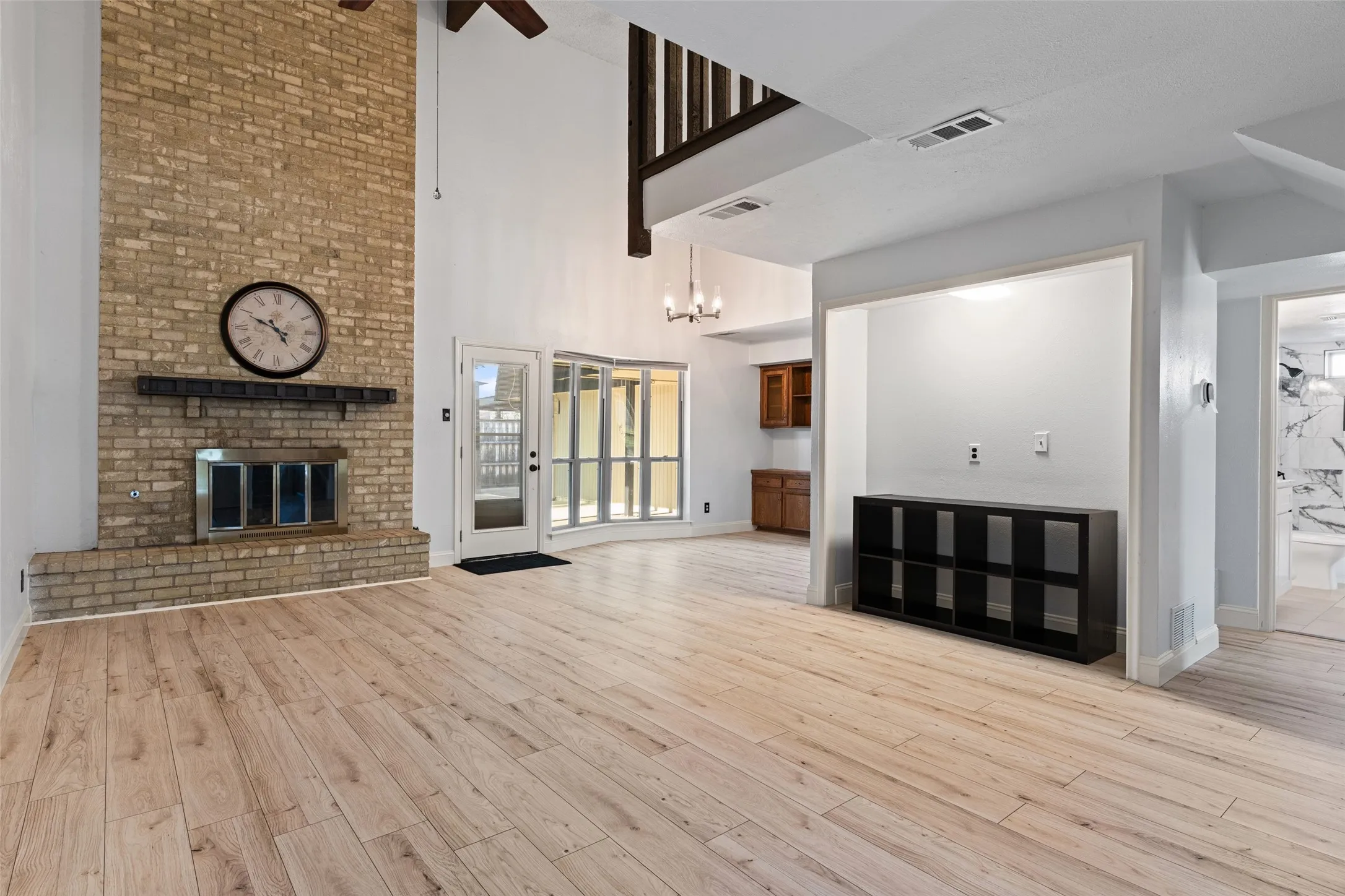 Two-story living area featuring a brick fireplace, wood-finish flooring, and a ceiling fan