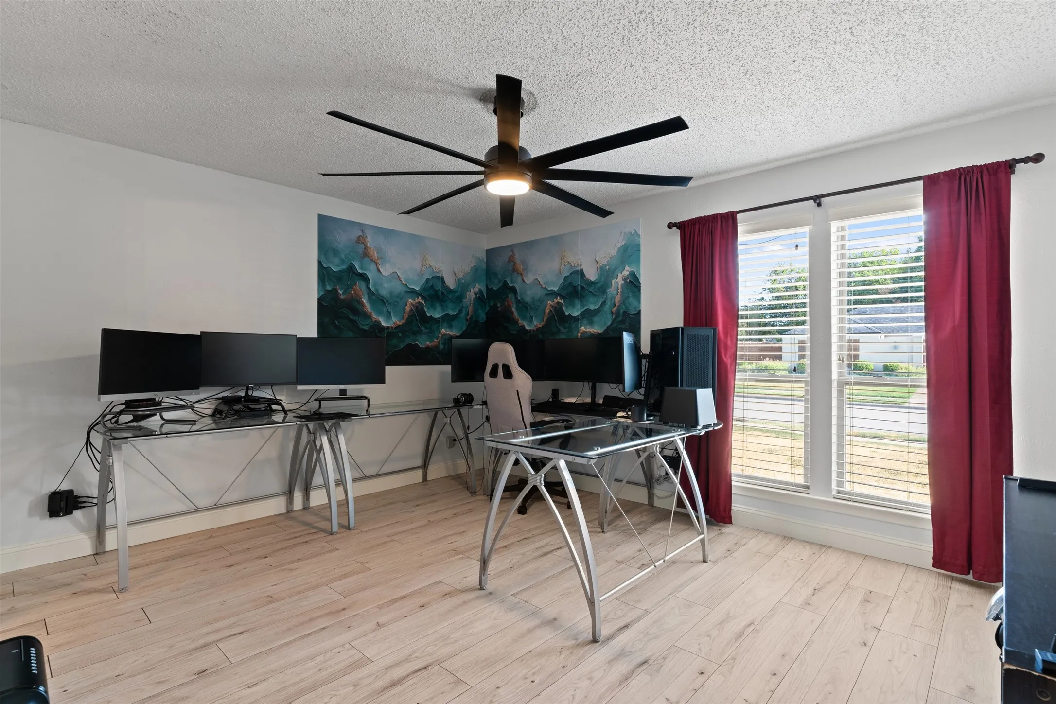 Wood-finish flooring with white baseboards, a ceiling fan with integrated lighting, and two windows with blinds