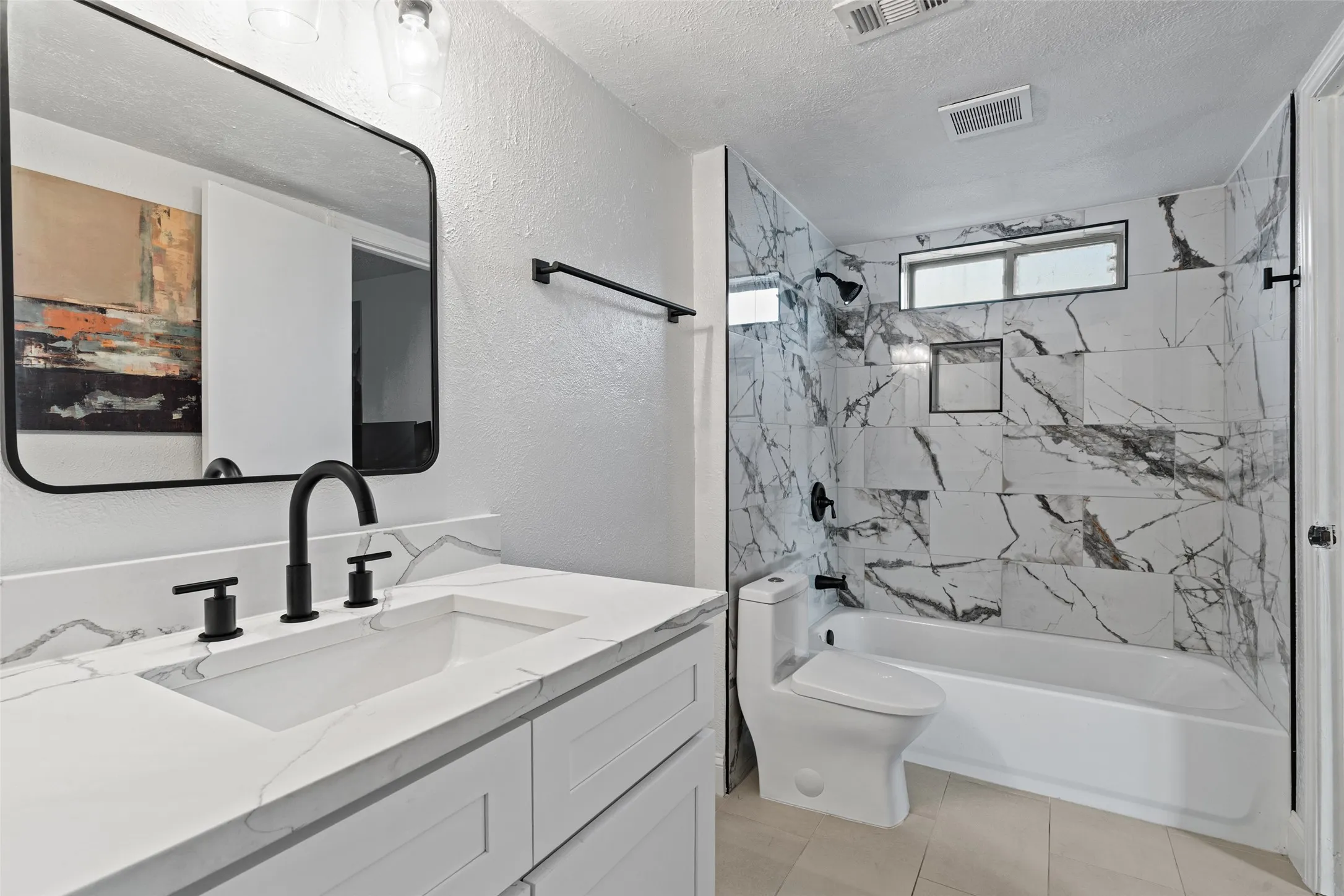 White vanity with integrated sink and matte black faucet, framed rectangular mirror, and white-and-gray patterned wall tiles