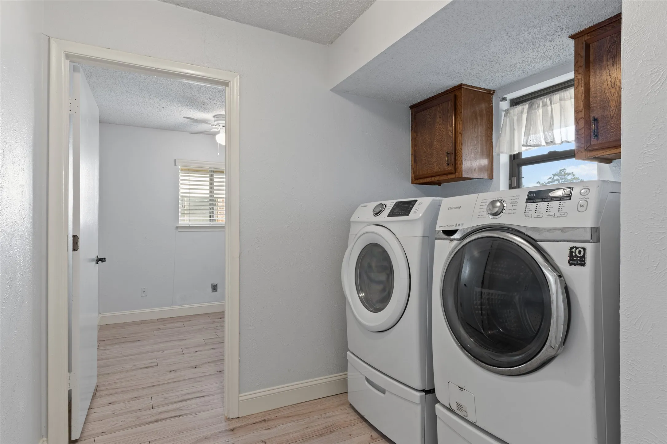 Laundry area featuring wood-finish cabinetry and a window