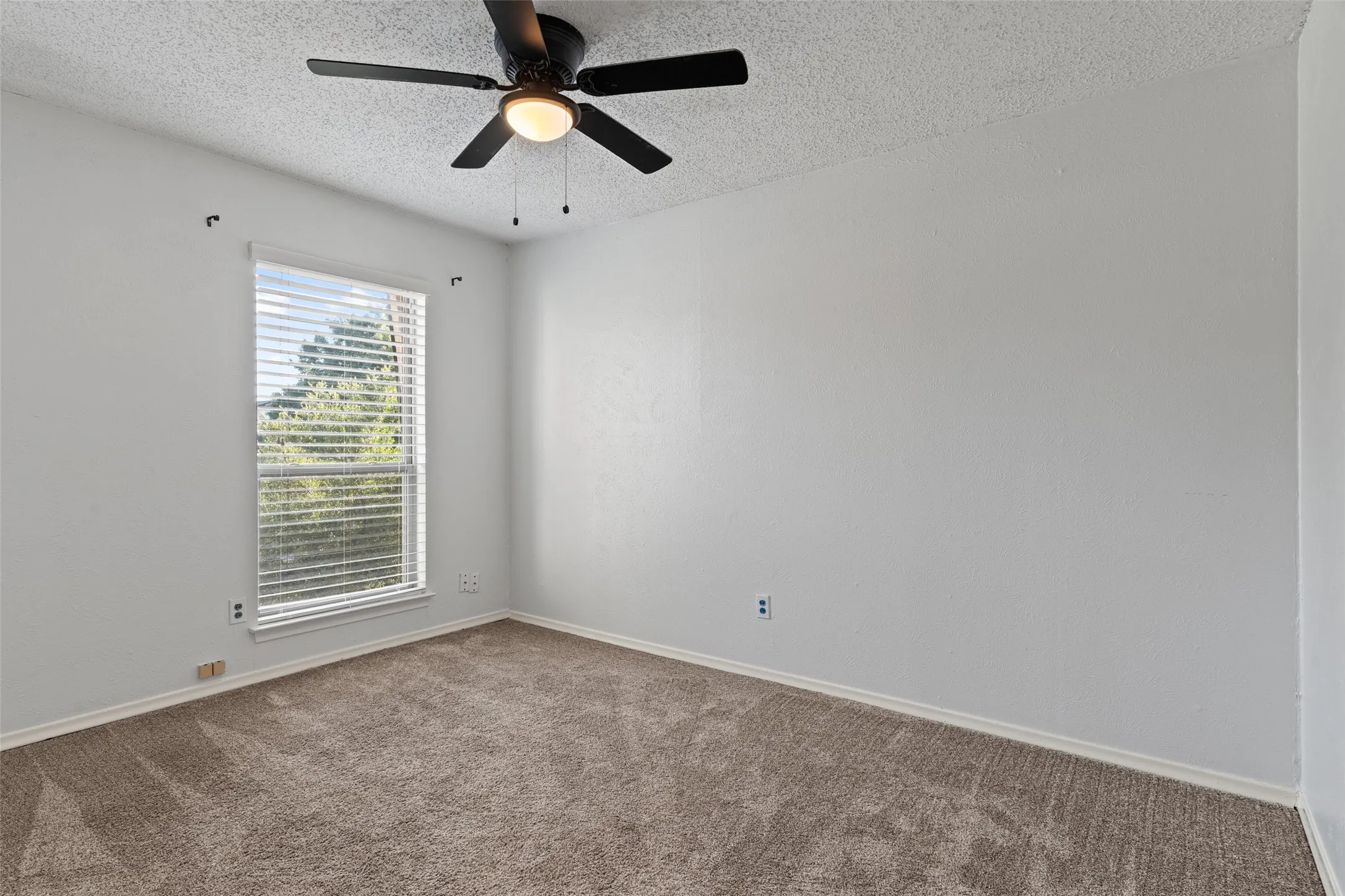 Carpeted flooring, window with blinds, ceiling fan with integrated lighting, and neutral wall finishes