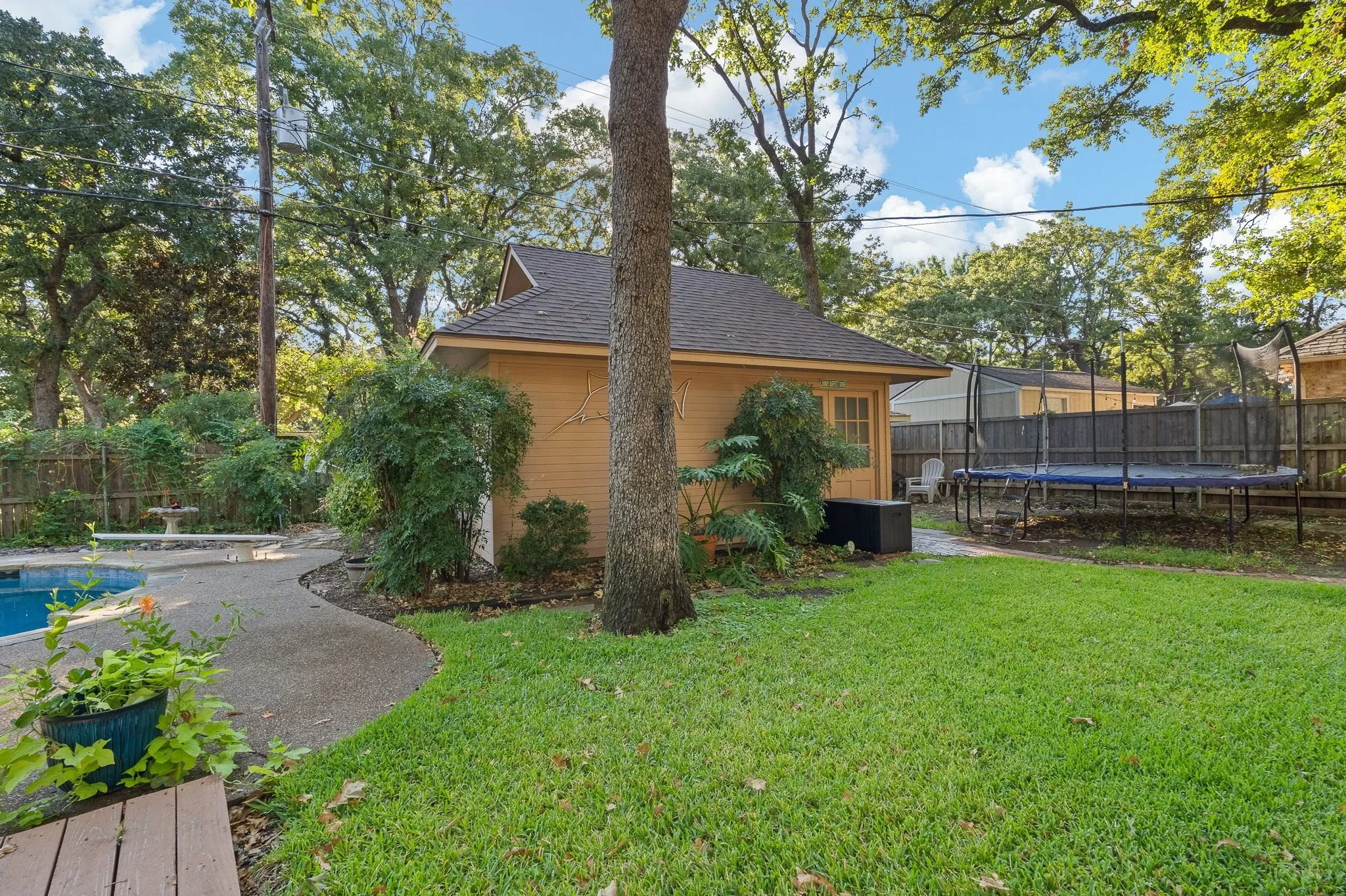 Rear yard featuring a detached structure with a pitched roof, a swimming pool, and a curved concrete pathway