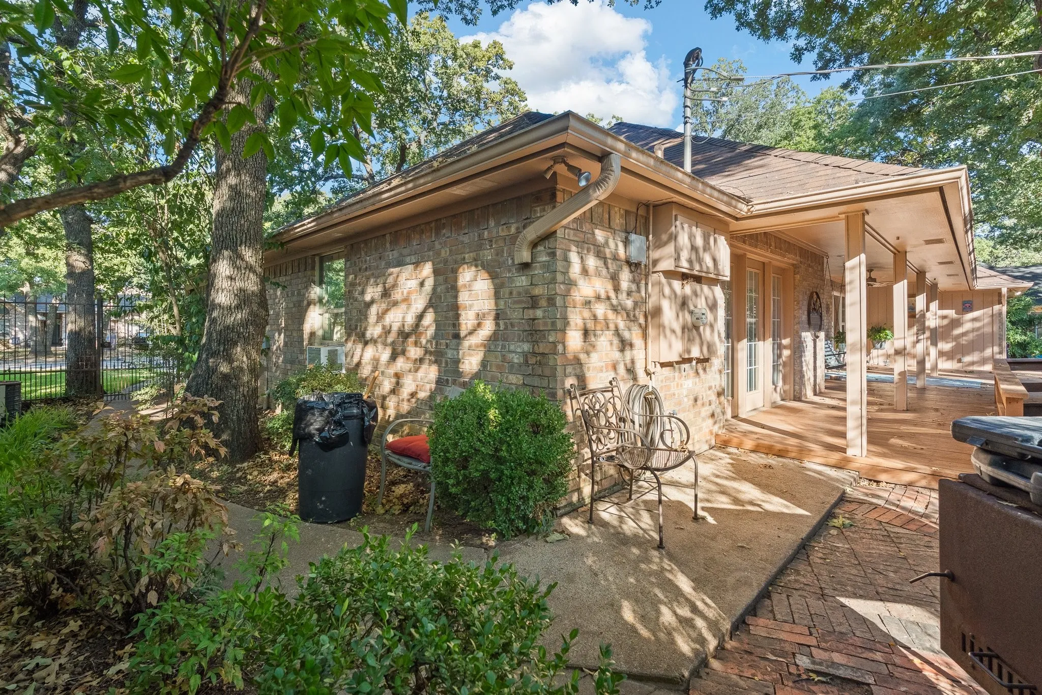 Brick exterior with a covered patio featuring a wood-finish floor and support columns
