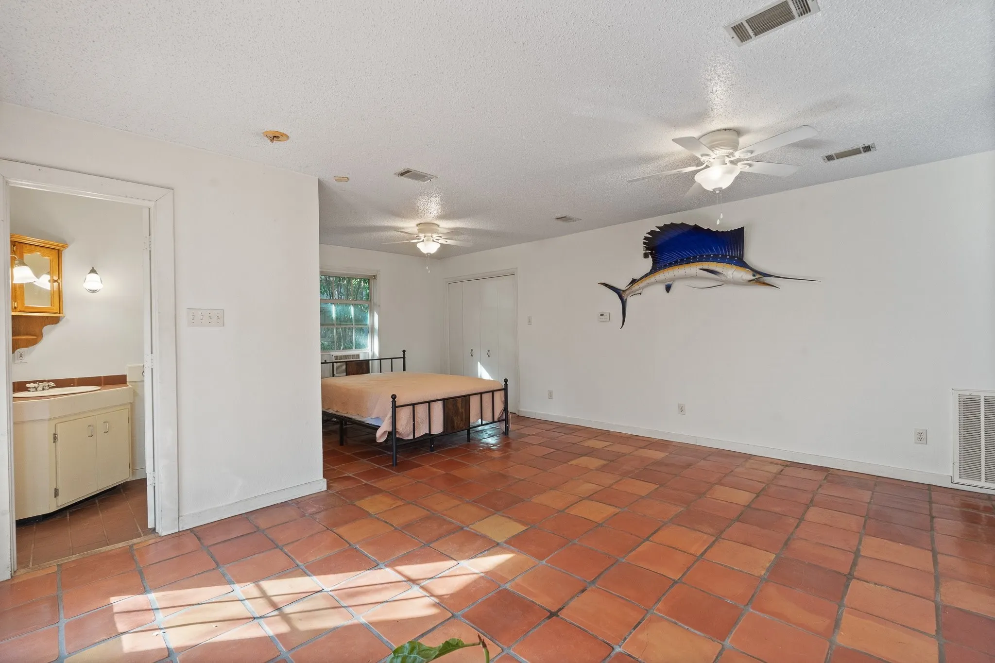 Spacious room featuring terra cotta tile flooring and a ceiling fan