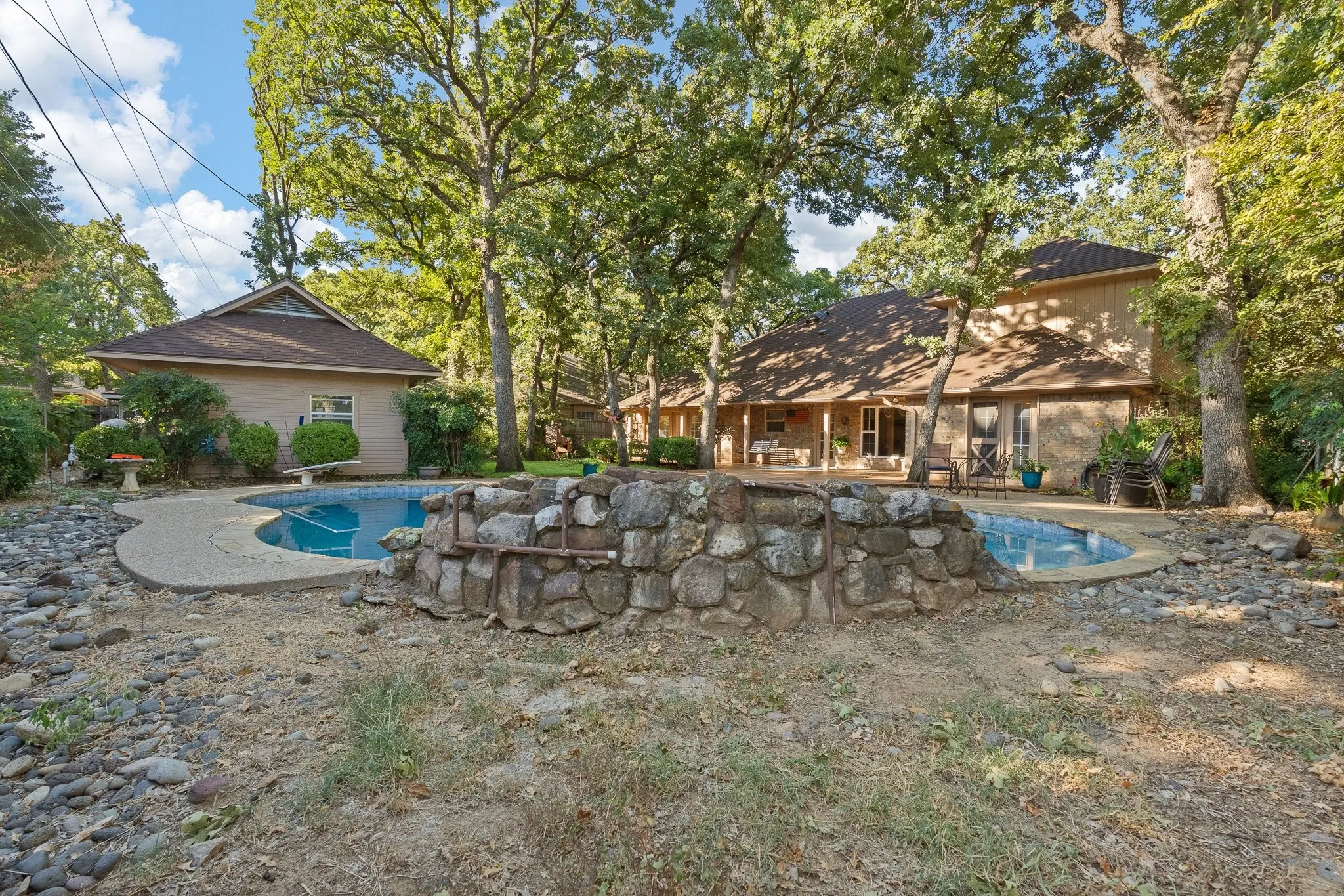 Swimming pool with surrounding concrete patio and stone-built feature