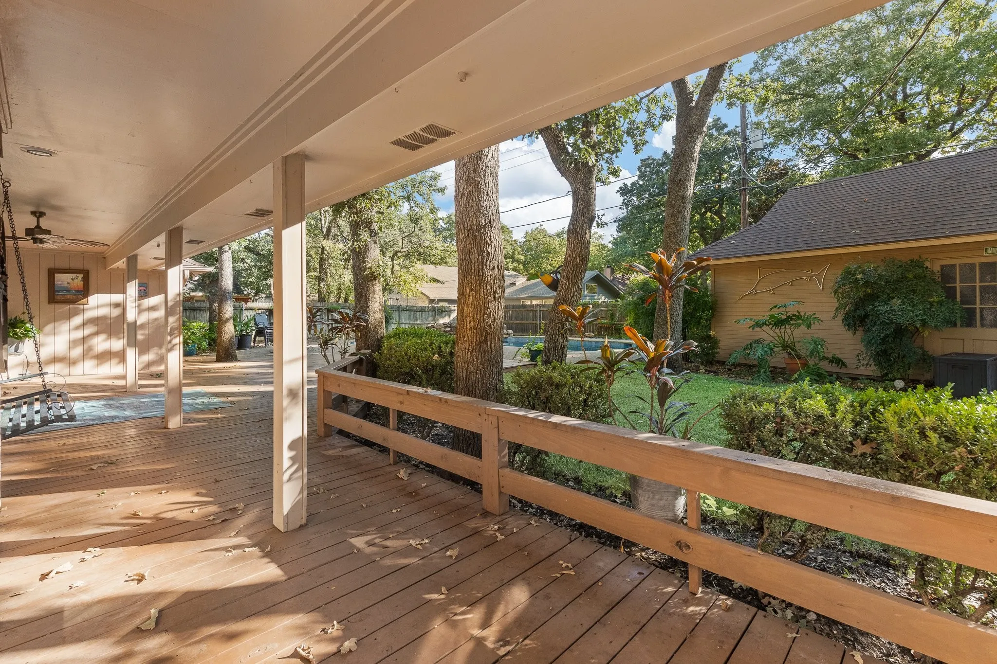 Expansive covered deck with wood-finish flooring and a partial railing