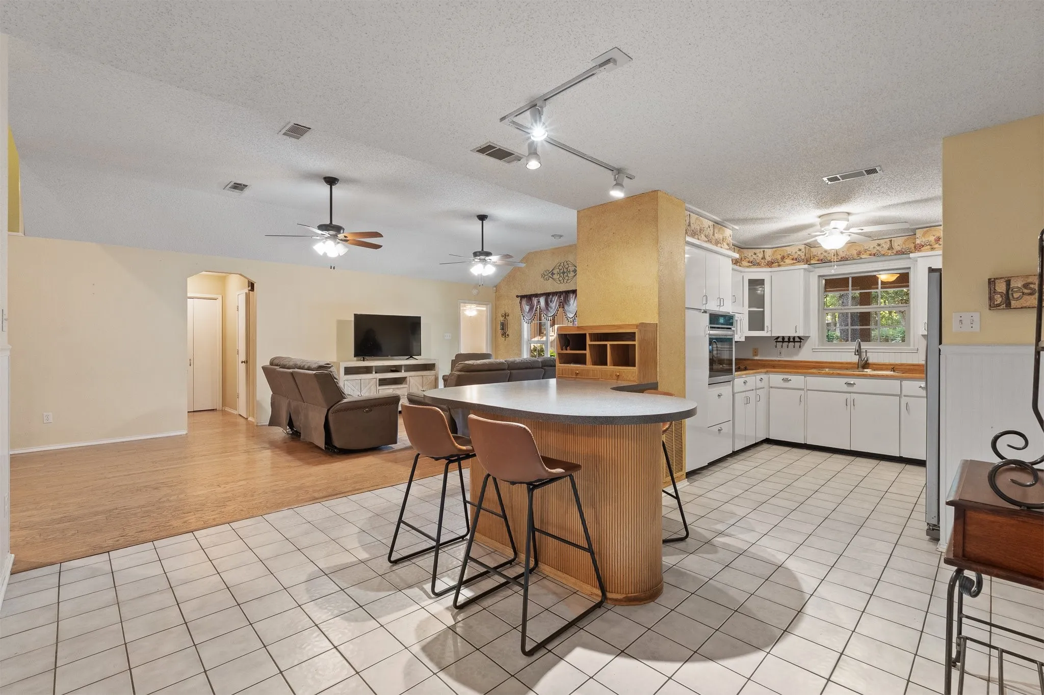 Kitchen with an eat-in island, white cabinetry, integrated appliances, and a window above the sink