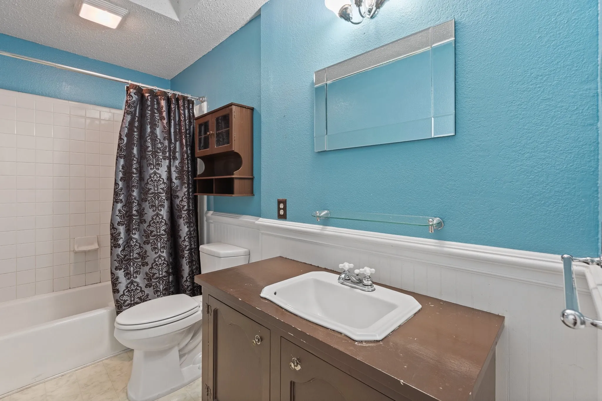 Built-in vanity with integrated sink, wall-mounted mirror, and overhead light fixture