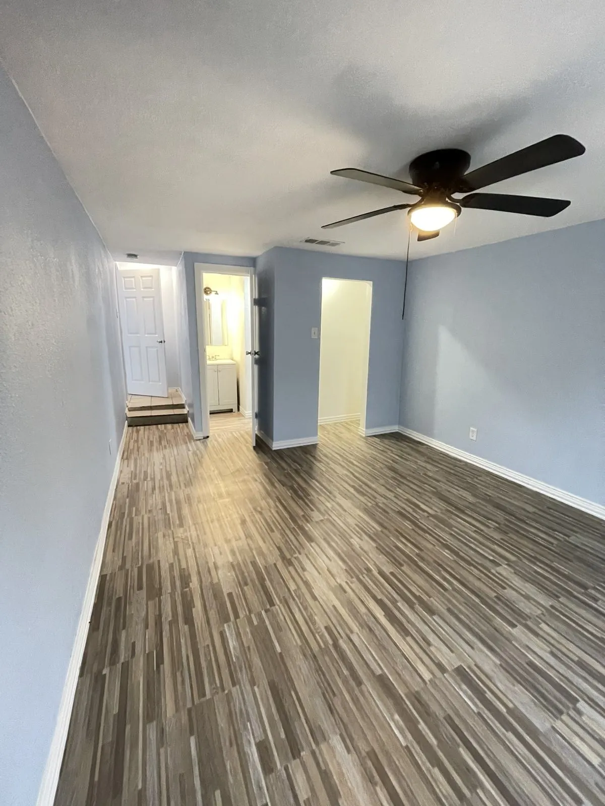 Unfurnished living room with dark wood-type flooring and a ceiling fan