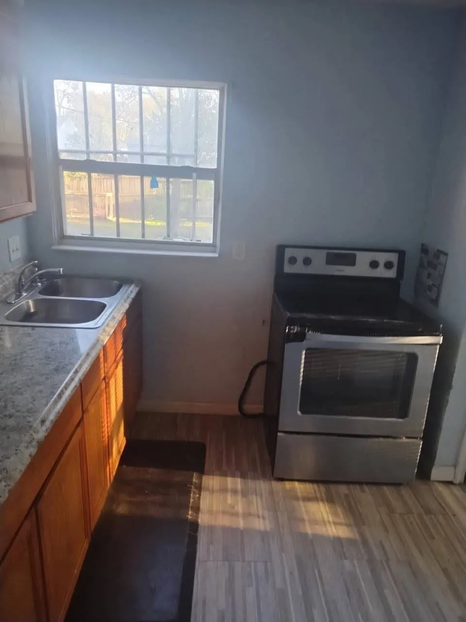 Kitchen featuring stainless steel range with electric stovetop, wood finish cabinets, dark wood-style floors, and light stone countertops