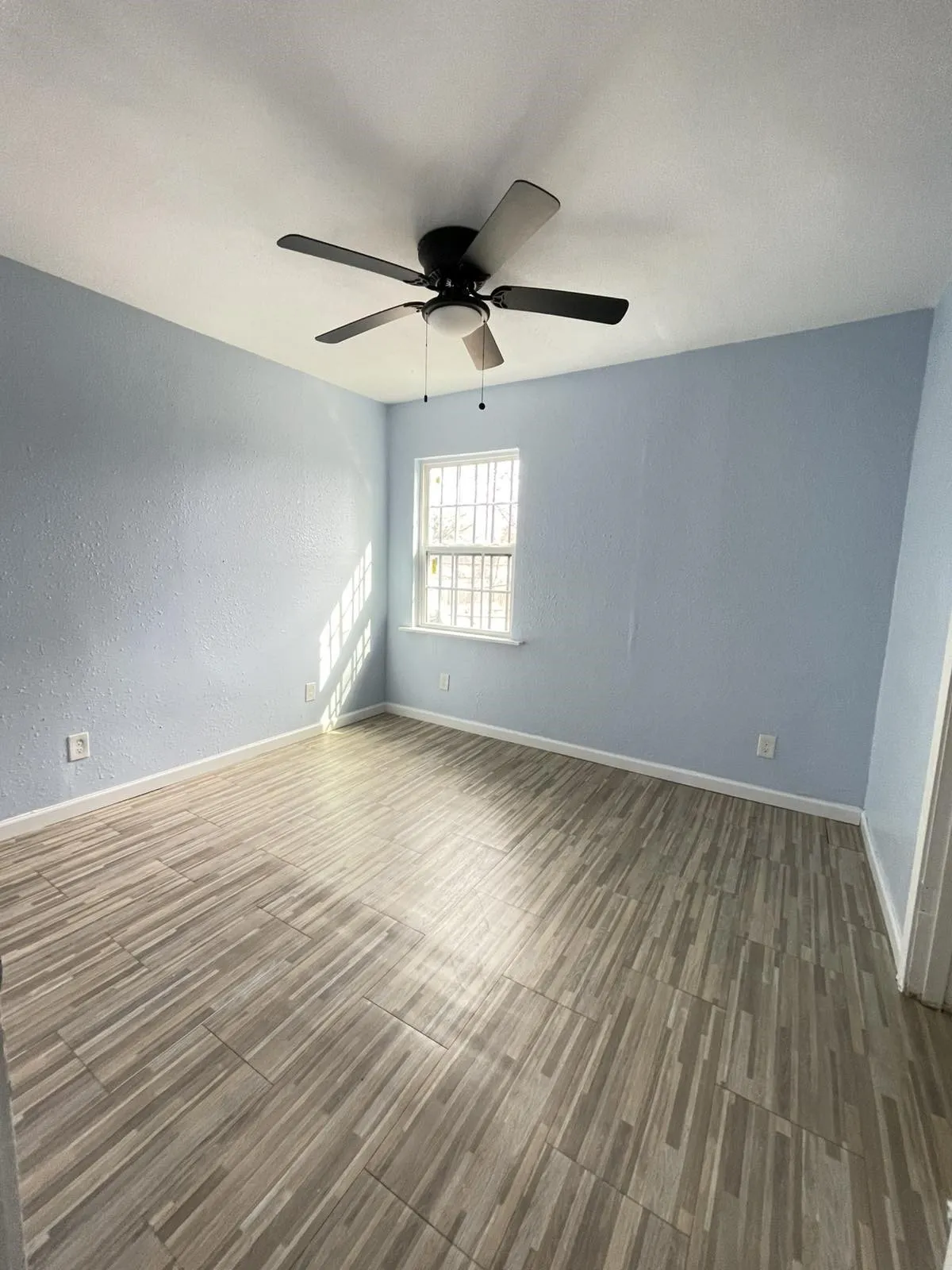 Empty room with wood finished floors, a textured wall, and ceiling fan
