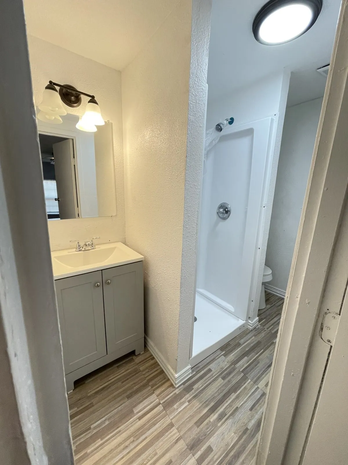 Bathroom featuring vanity, a shower stall, light wood finished floors, and a textured wall