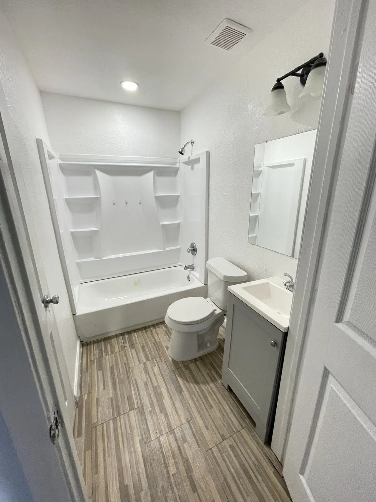 Full bathroom with vanity, shower / tub combination, and light wood-type flooring