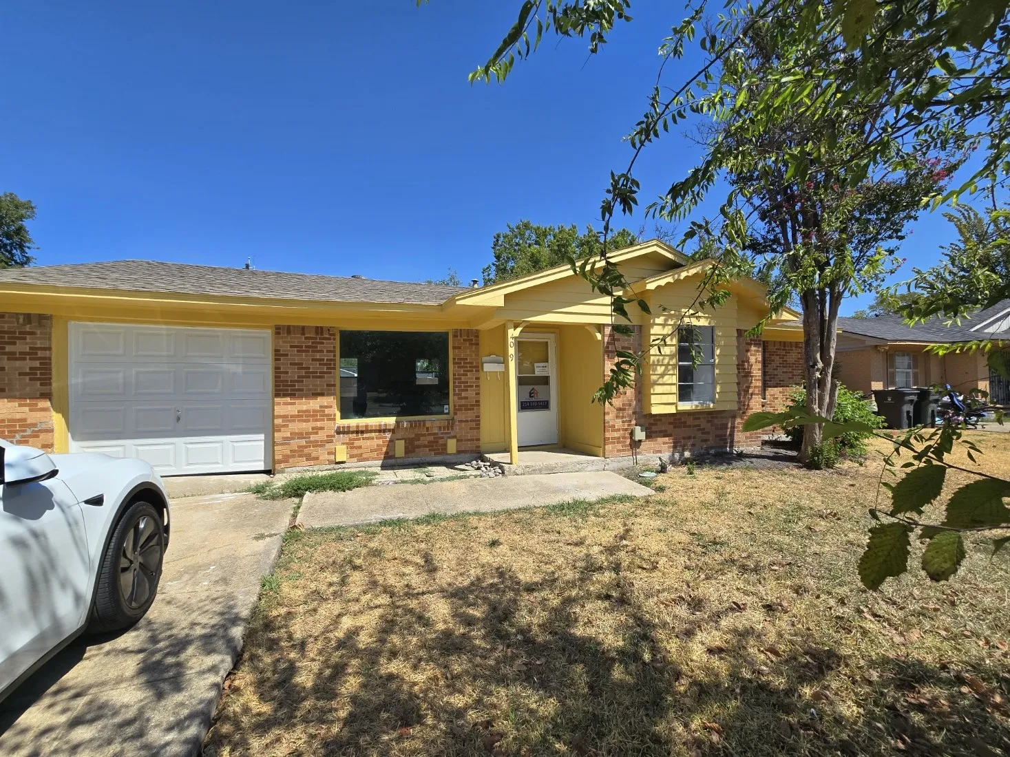 Brick exterior with yellow siding accents, an attached garage, and a concrete driveway