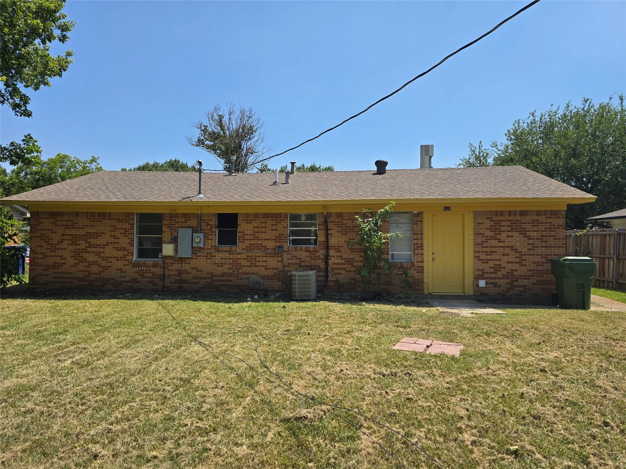 Brick exterior with a brown shingle roof, yellow trim, and a yellow door