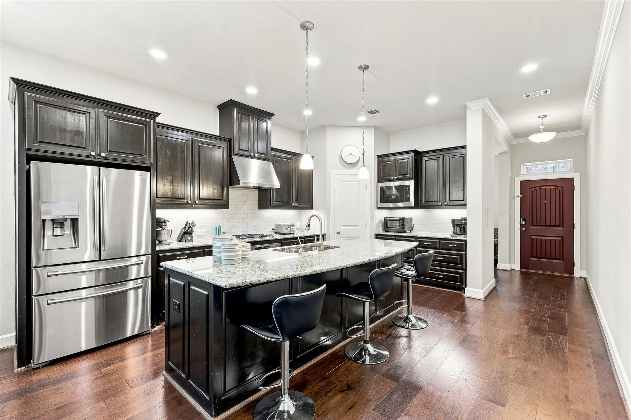 Gourmet kitchen with dark wood cabinetry, stainless steel appliances, a center island featuring a light-toned countertop, and recessed lighting