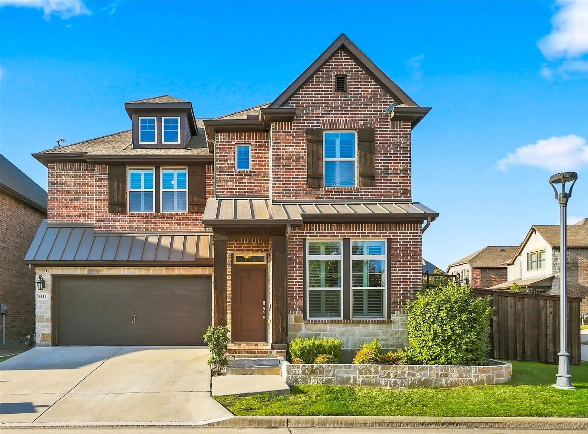 Brick exterior with stone accents, gable roof, dormer window, covered entry, and attached garage